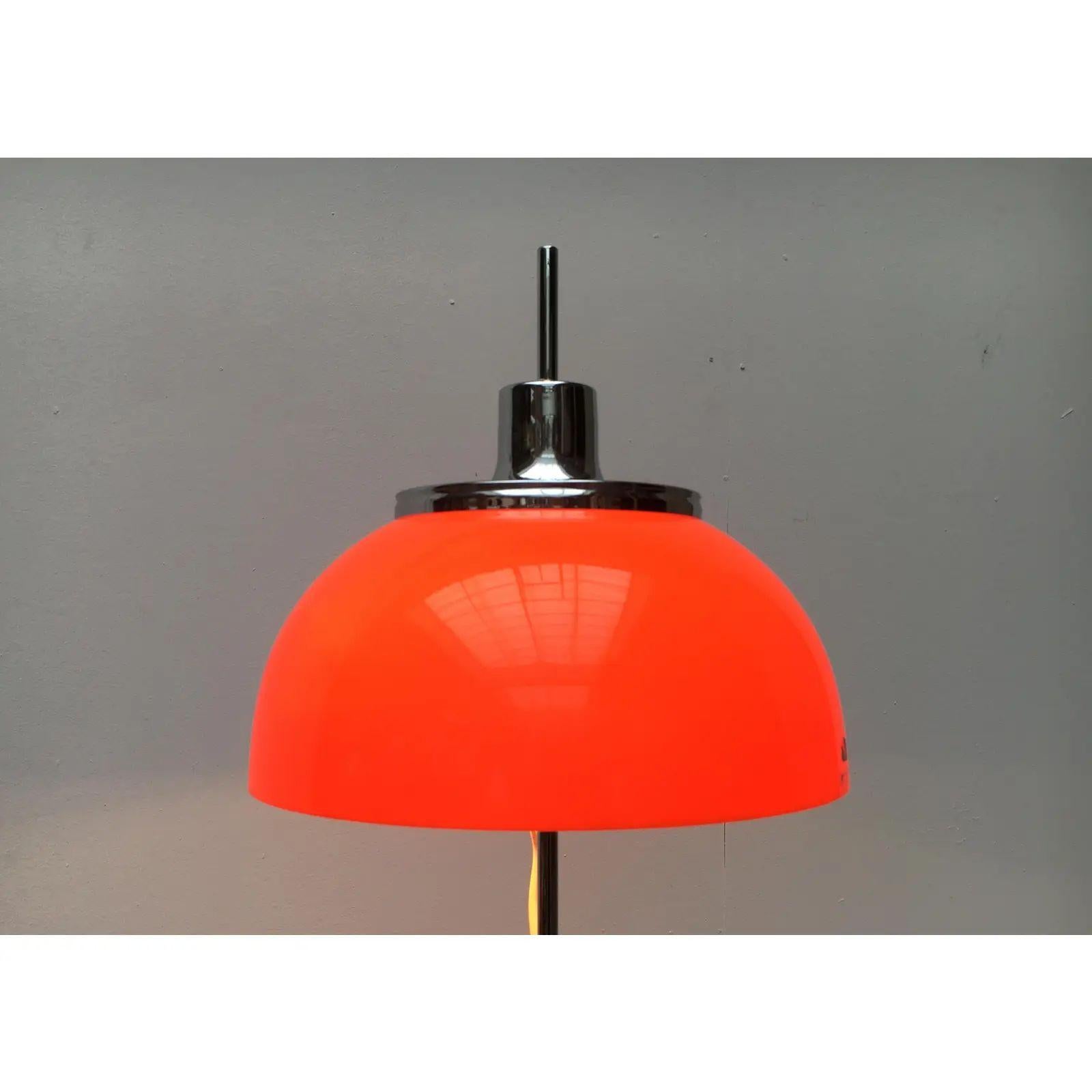 Faro table lamp by Harvey Guzzini. Here is an early version (Art. 2248) from the production period of 1970 - 1972.

The lampshade is mushroom-shaped and designed in two parts. Above the orange acrylic shade protrudes a chrome-colored metal hood. The