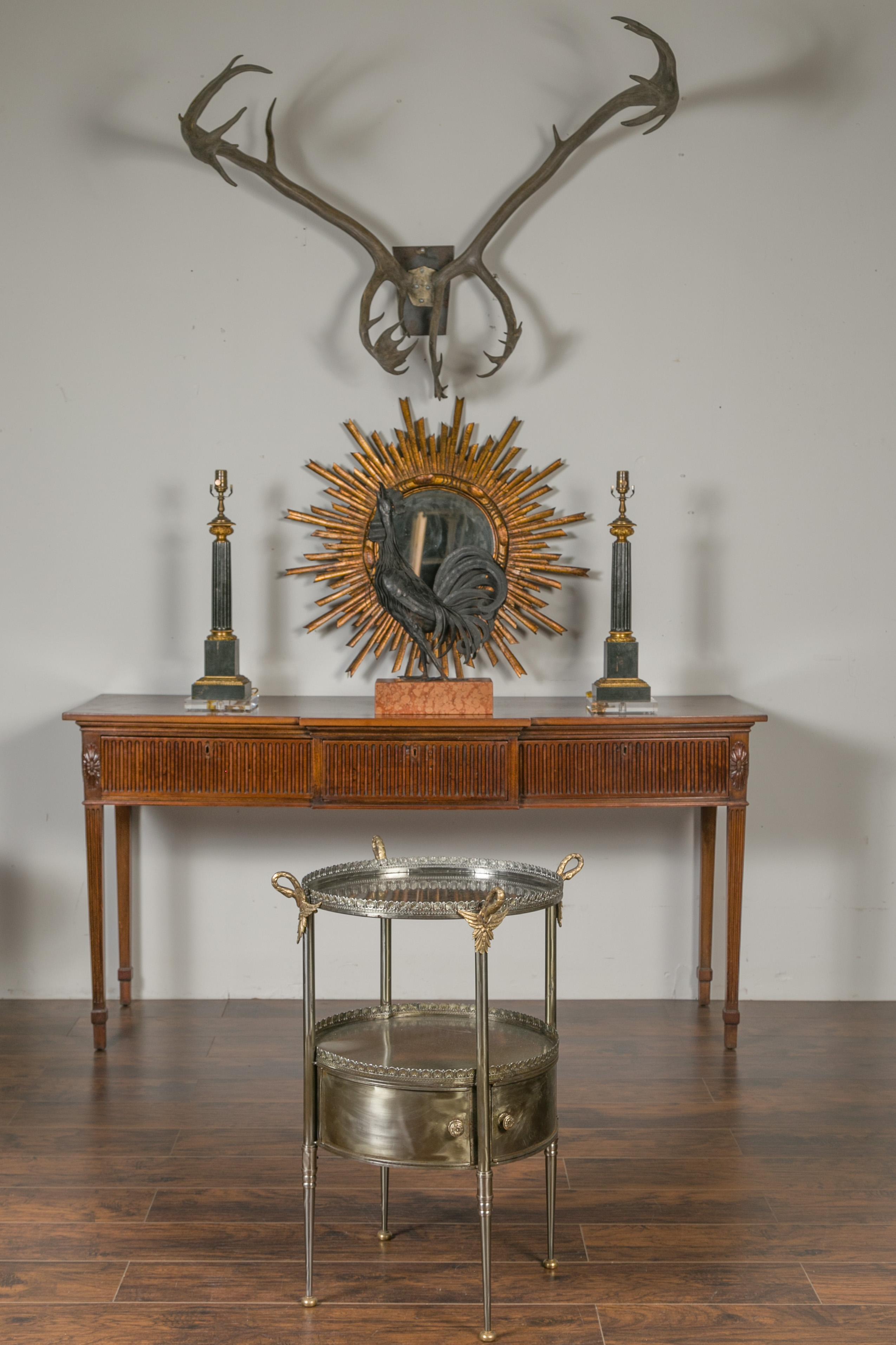 A vintage Italian steel and bronze round top side table from the mid-20th century with two doors, swan necks and wing motifs. Born in Italy during the midcentury period, this steel side table features an exquisite circular top, adorned with petite