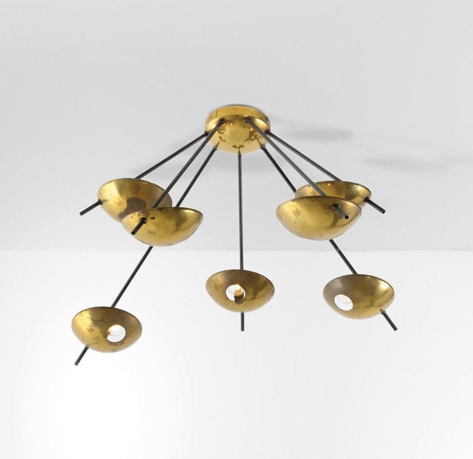 Luminaire vintage (pouvant être monté aussi bien au plafond qu'au mur) en laiton poli, sept douilles et sept coupoles en laiton maintenues par de fins bras en métal émaillé. Fabriqué en Italie, C.I.C., vers 1960, par Stilnovo. 'Apparaît dans