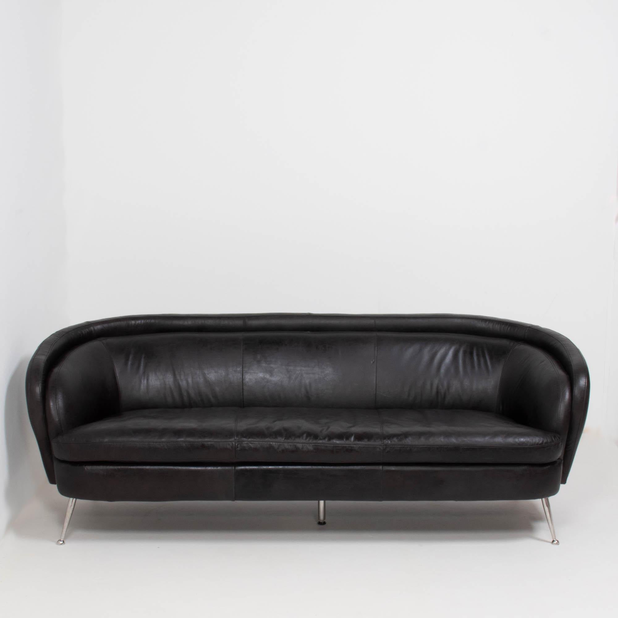 Beautifully curved, this 1960s vintage sofa is upholstered in black leather and sits on chrome stiletto legs with an additional central support.

The back of the sofa is curved, creating a striking silhouette. The single back cushion, follows the