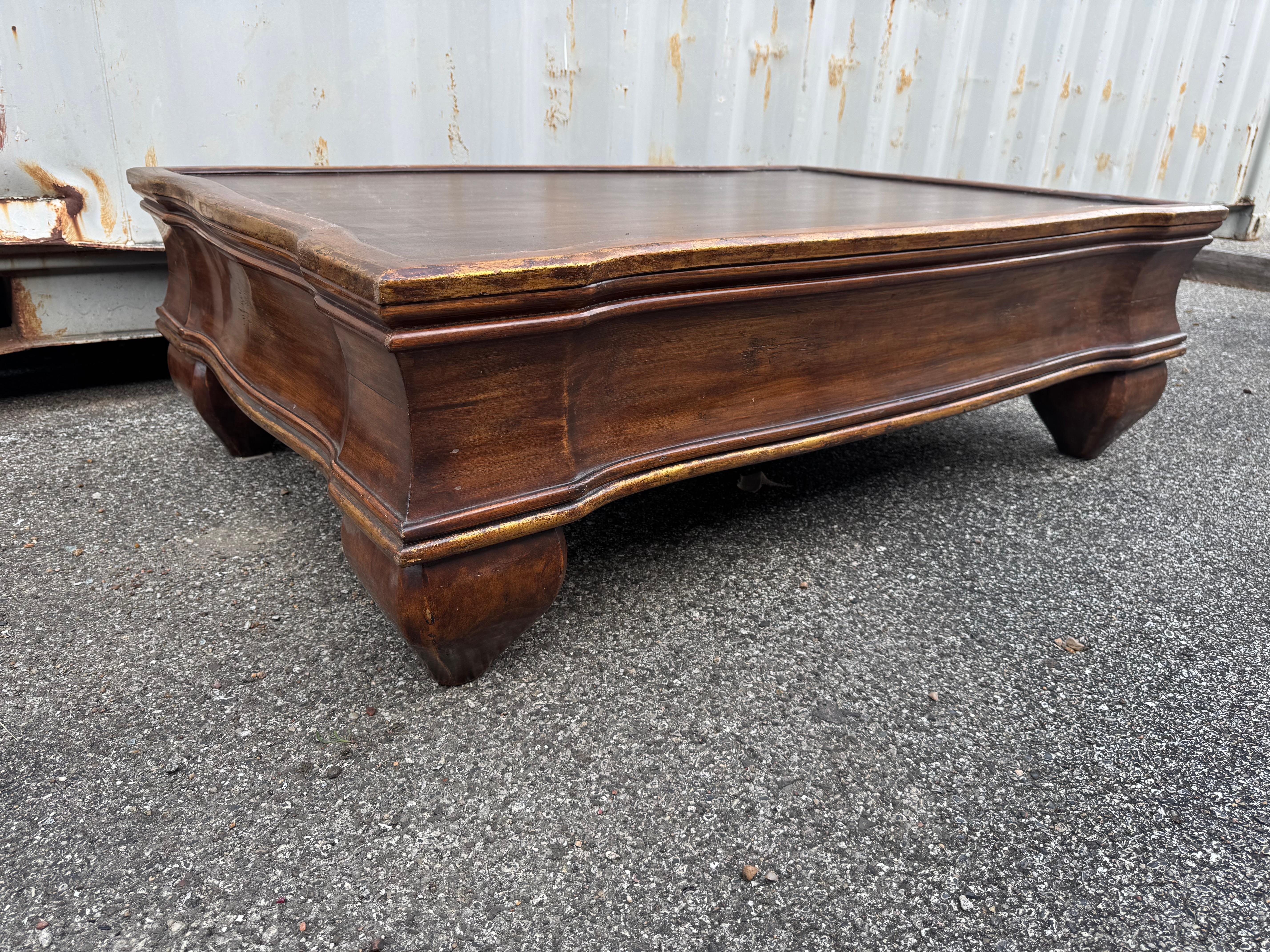 This is quite an unusual style coffee table.
It made of Pitch Pine and has gold gilt along the edges.
The legs are bulbous and it has a thick skirt.
The piece is well made but bears no manufacturers mark.