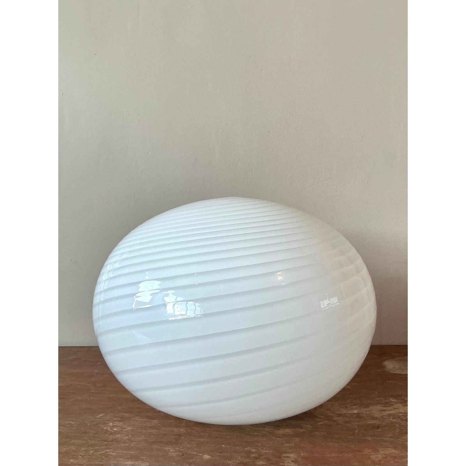 Esta lámpara de mesa italiana vintage, que irradia un resplandor suave y etéreo, es un impresionante ejemplo del arte en vidrio de la modernidad de mediados de siglo. Soplada a mano por expertos al estilo de los mejores artesanos de Murano, la