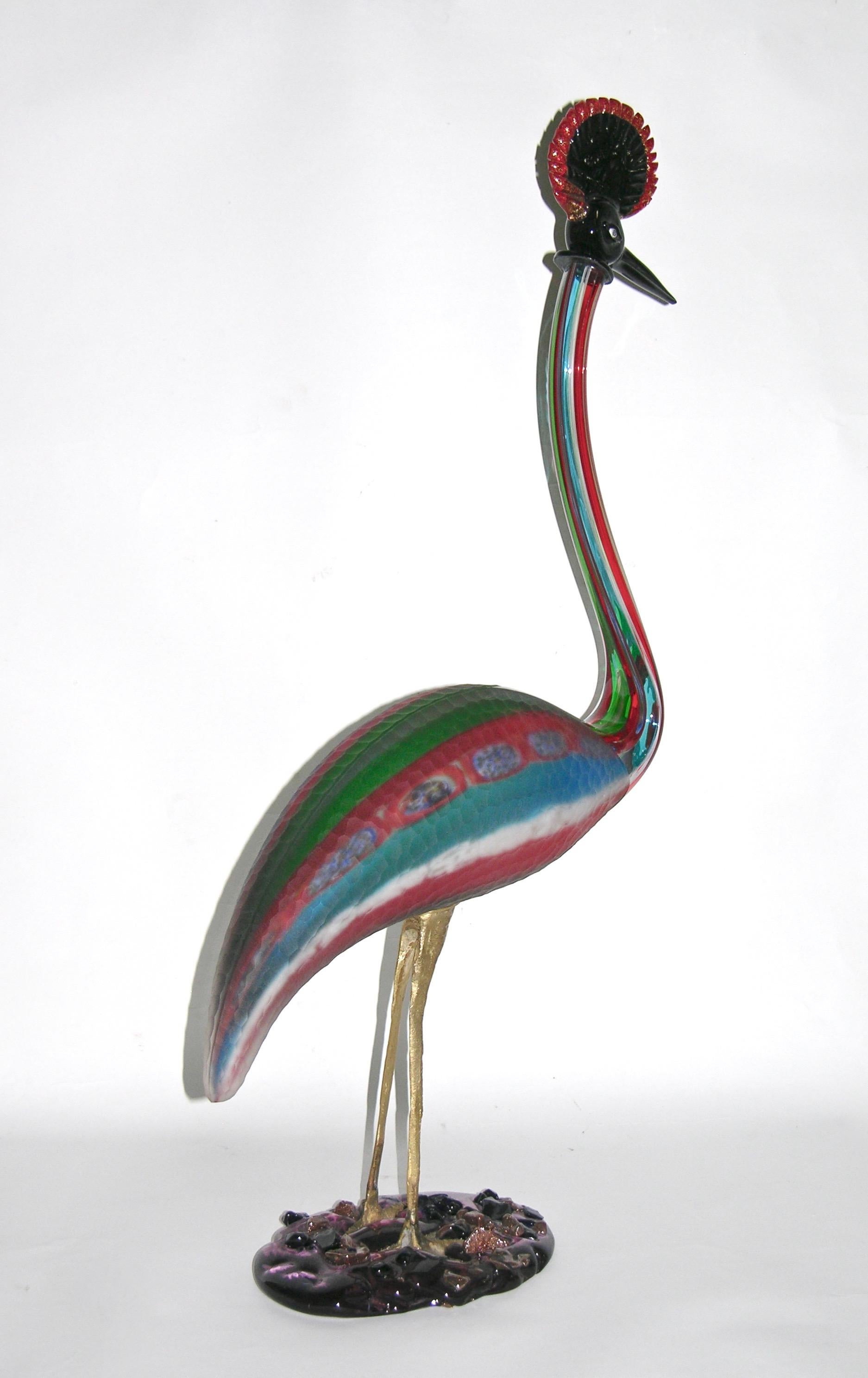 This very expressive crested crane art glass sculpture, from the 1970s, is a true jewel-like work of art, in sophisticated blown Murano glass, with overlaid stripes decor in red, white, blue and green, with inserted multi colored murrine and part of