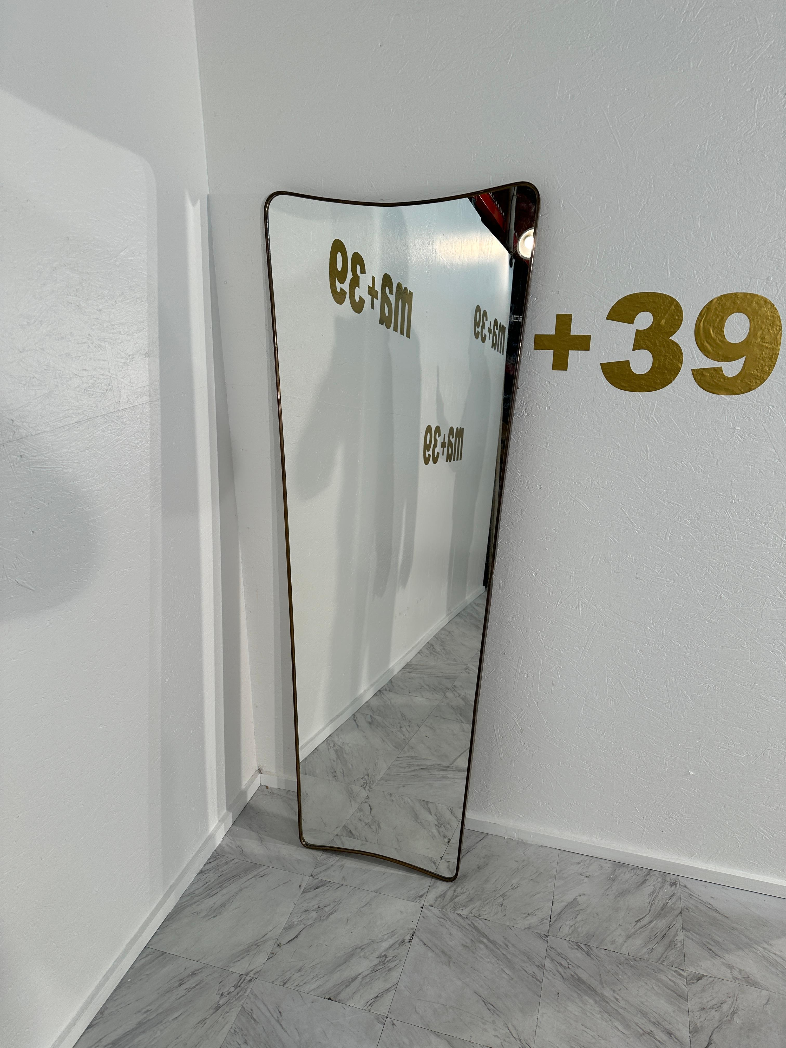 The Vintage Italian Tall Wave Wall Mirror from the 1960s features an elegant brass frame with an original patina, exuding timeless charm and sophistication. Its unique wave design adds a touch of artistic flair, making it a captivating focal point