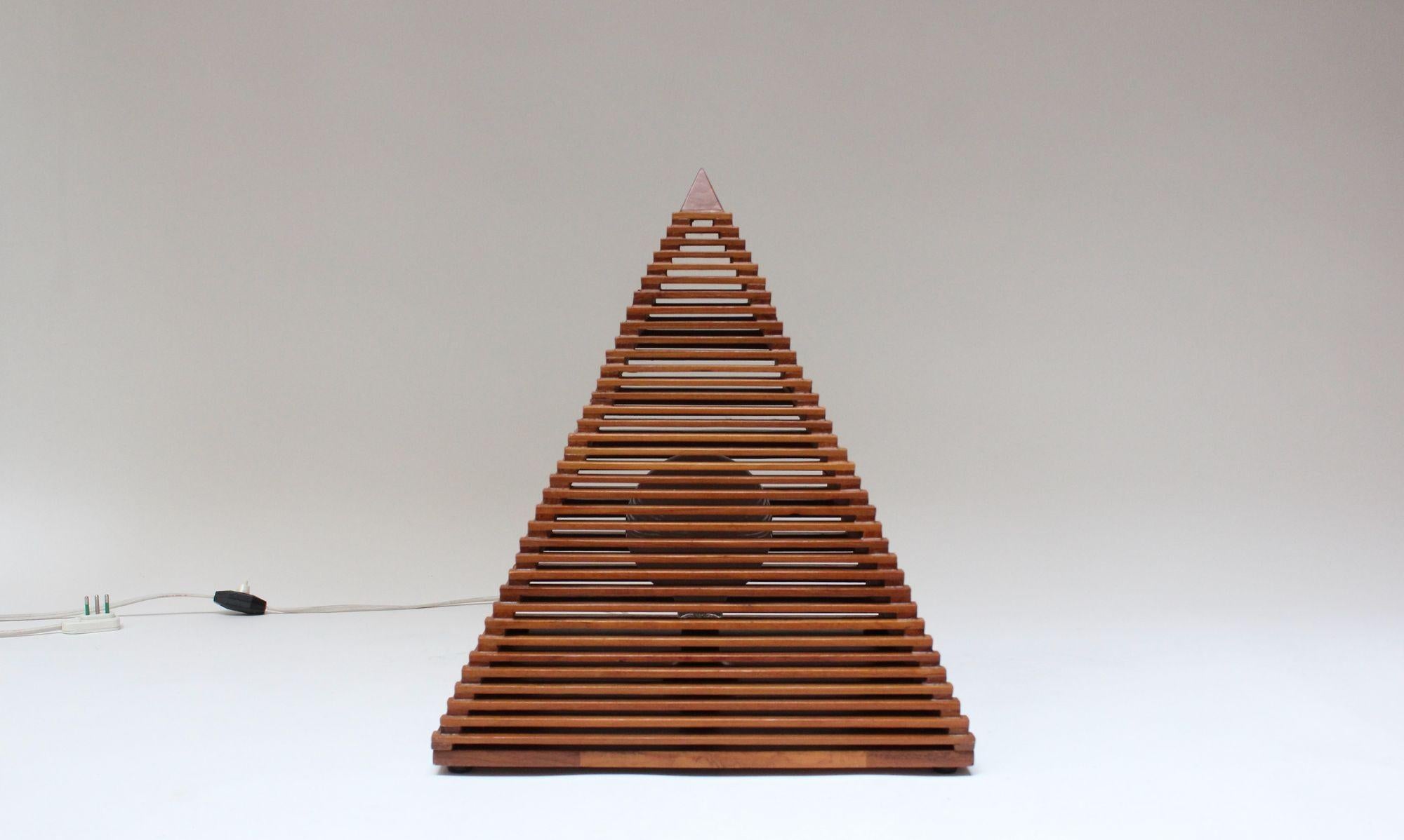 Vintage pyramid lamp composed of a slatted teak pyramid-form top supported by a staved-teak square base (ca. late 1970s, Italy).
Since the pyramid portion isn't mounted to the base, it can be removed and positioned as desired.
Very good, vintage