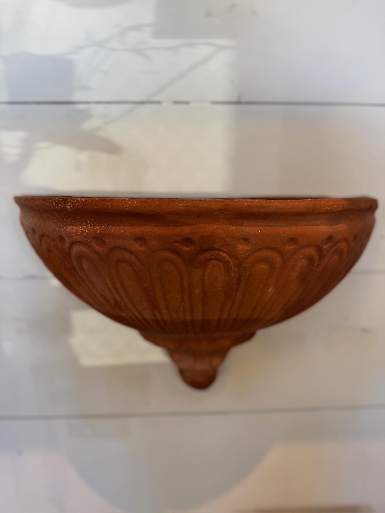 This vintage Italian terracotta wall pocket planter is a beautifully handcrafted piece, reminiscent of traditional Tuscan and Mediterranean garden decor. Featuring an elegant fluted relief design, this planter has a timeless charm, ideal for adding