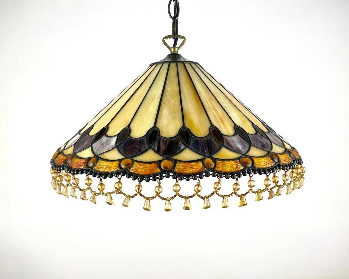 Stained glass Tiffany chandelier geometric art deco with fringle on the shade. Brown, yellow and ocher glass according to the traditional technique of the first manufacturer Louis Comfort Tiffany.

Chandelier is handcrafted by hundreds of