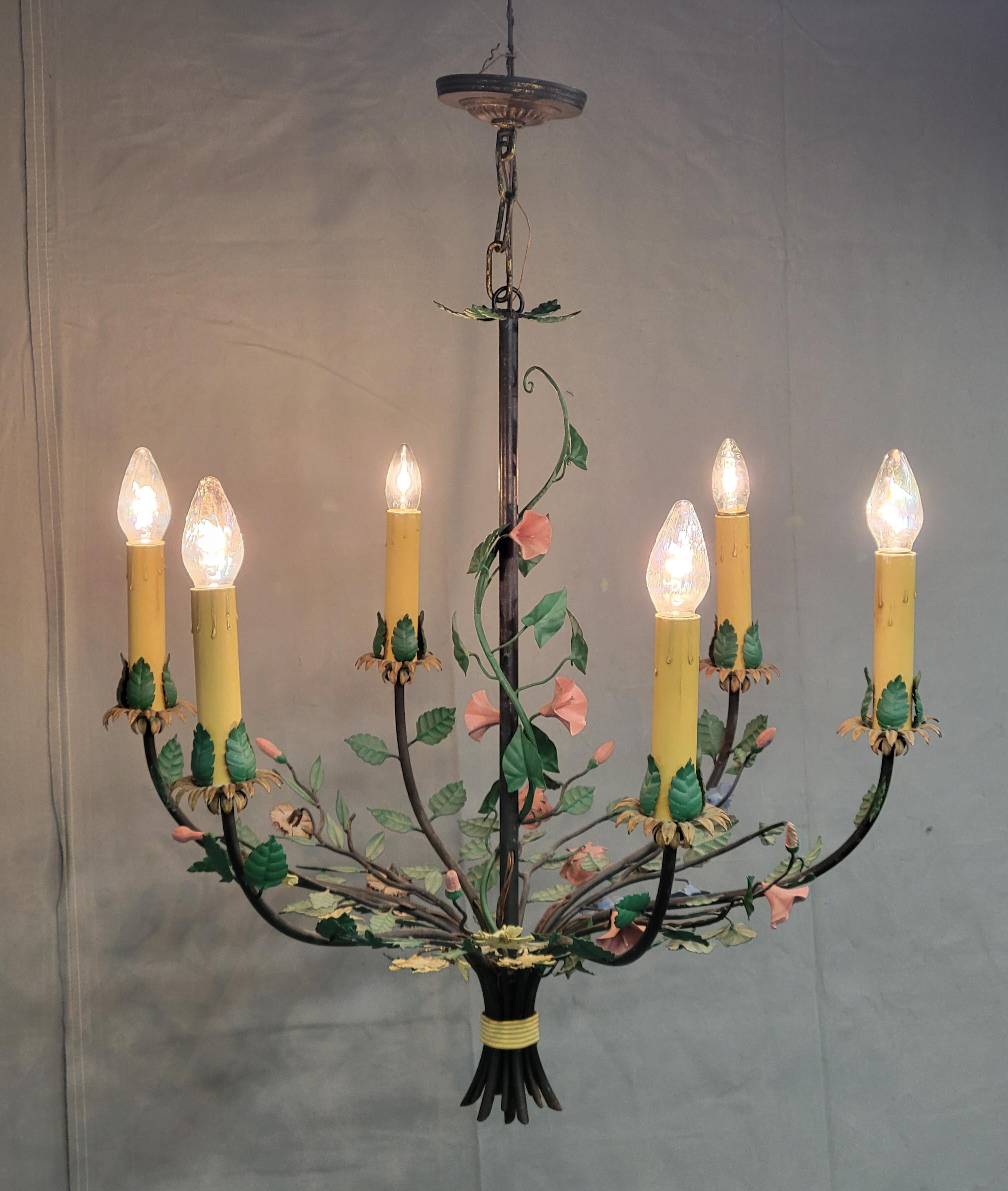 Just in time for spring, a truly charming vintage Italian tole chandelier crafted out of black wrought iron and decorated with beautifully painted flowers in shades of green, pink, blue and yellow. Likely from the 1950s, or perhaps earlier, this