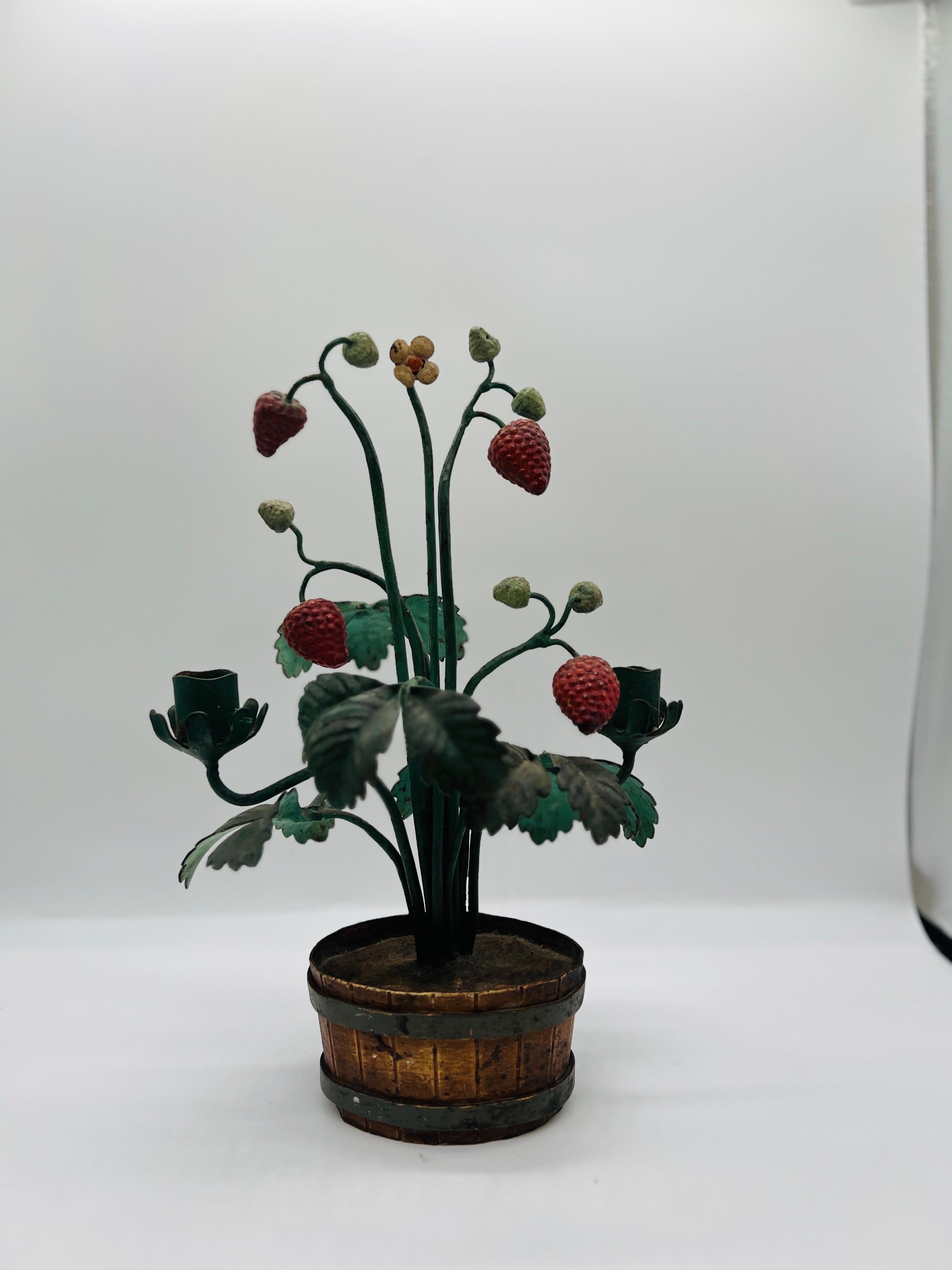 Italian, mid 20th century.

A vintage Italian hand painted tole topiary depicting a strawberry bush blooming inside a iron banded basket. Two wrought iron candlestick arms mounted. Apparently unmarked. 
Heavy and good quality. 