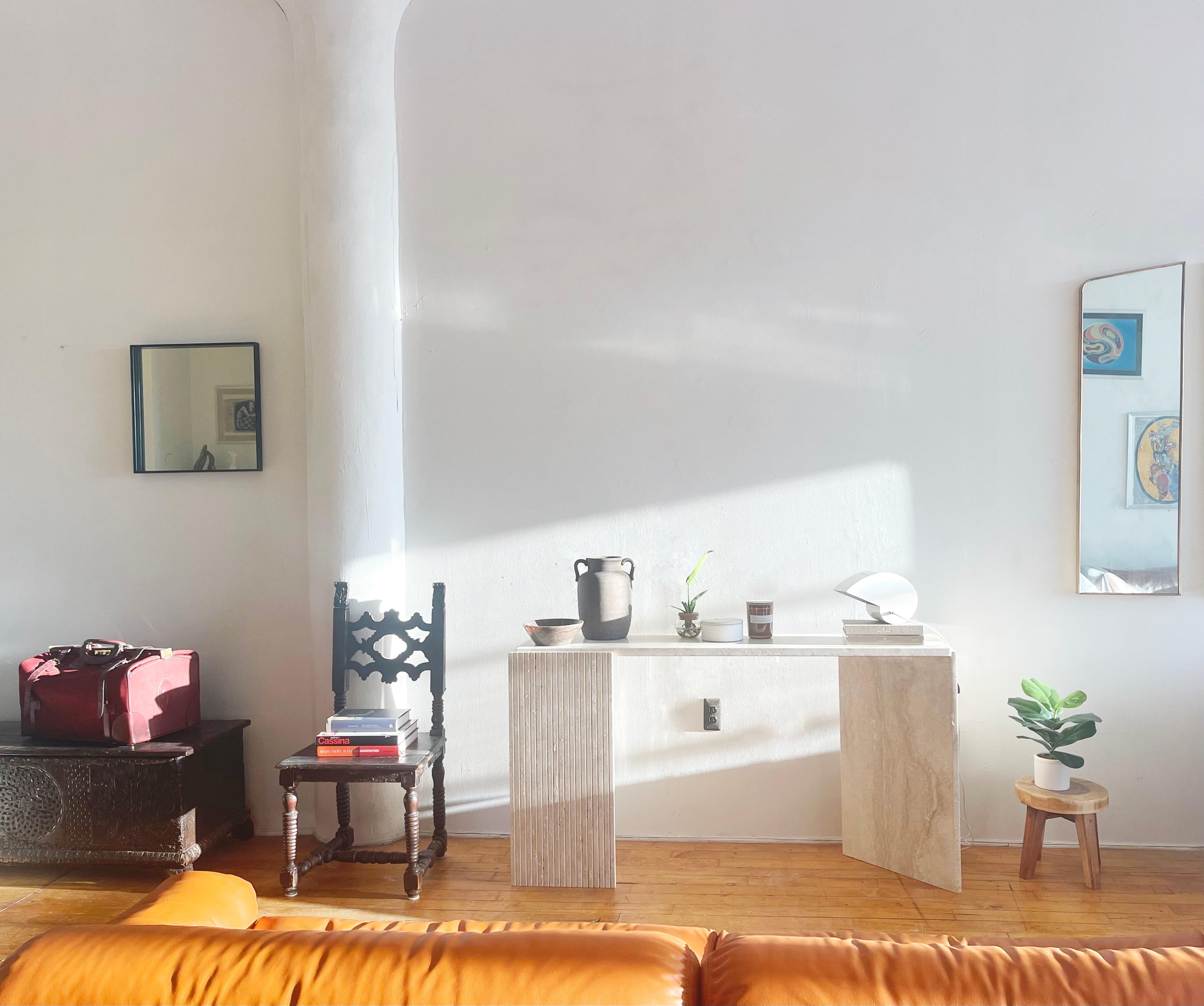 Italian vintage travertine console table with sculptural legs and an elegant sleek top. This remarkable console table which we sourced in Italy embodies a captivating interplay of textures and shapes, seamlessly blending the smooth top with the
