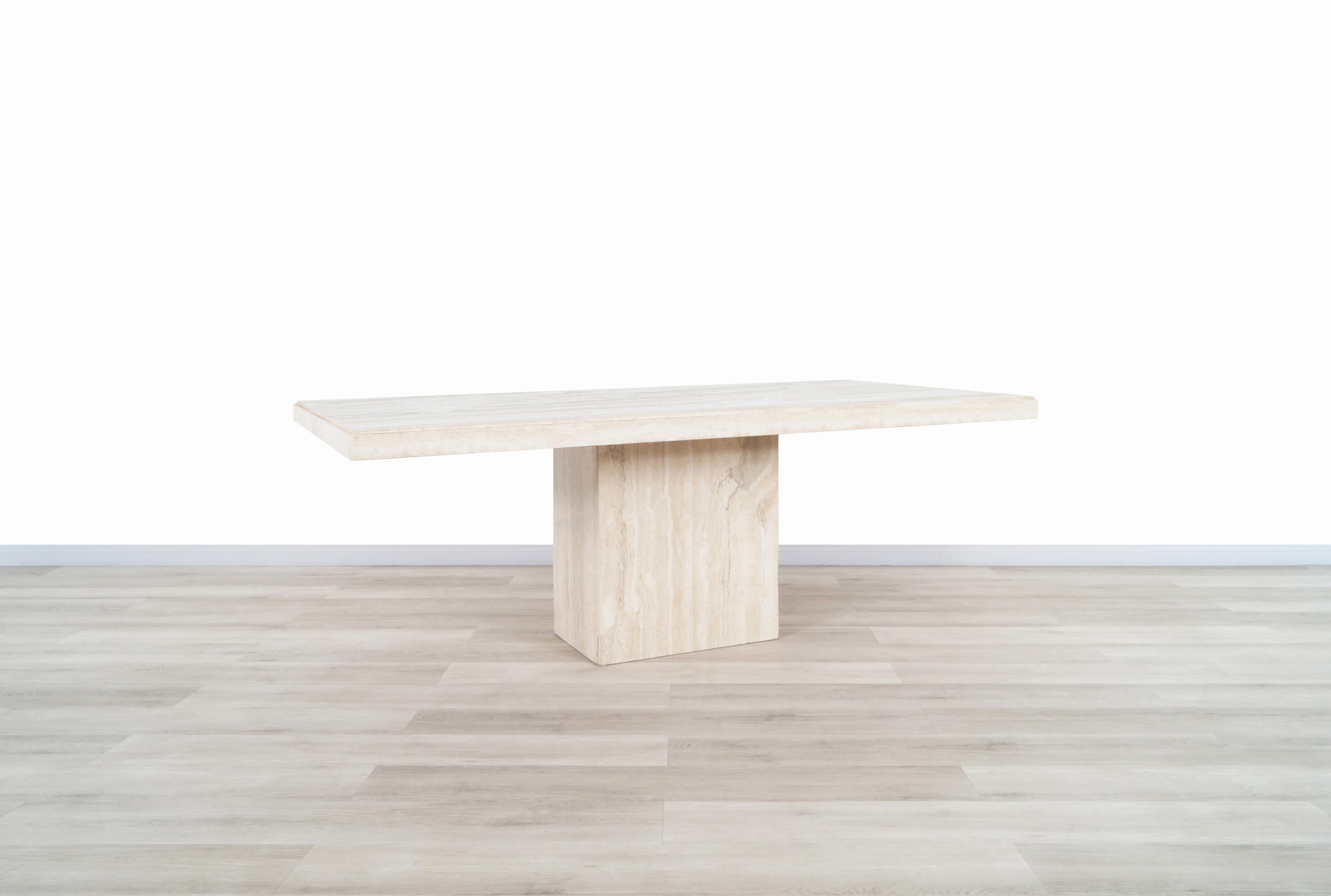 Stunning vintage modernist travertine dining table manufactured in Italy, circa 1970s. This table features a gorgeous rectangular travertine top that sits over an extremely sturdy base and is complemented by the natural minerals of the travertine