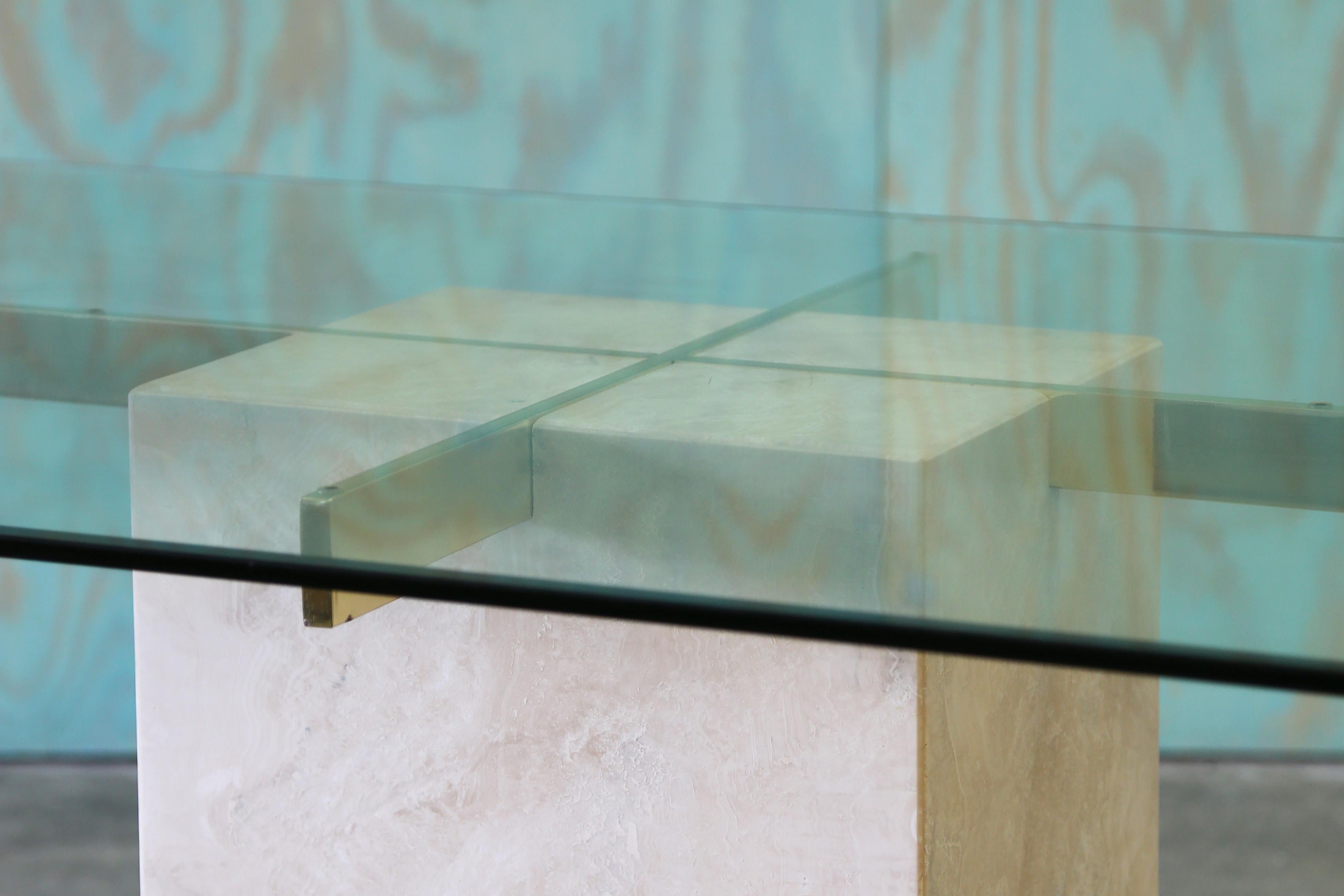A travertine and brass dining table attributed to Artedi circa 1980s.  A minimalist postmodern feel combining natural materials of travertine and glass.  The brass coated steel supports seemingly built in to the travertine base.  

Unsigned.