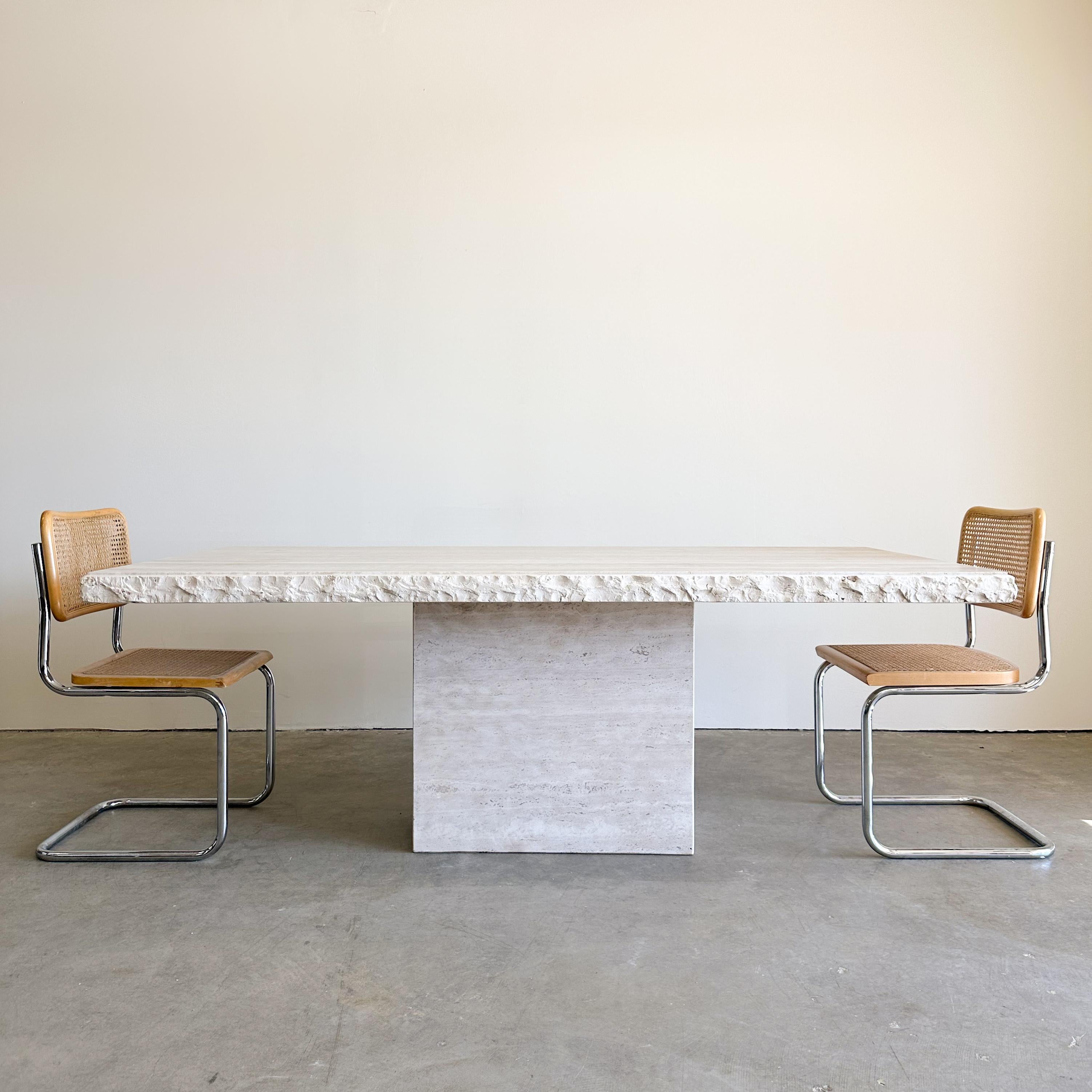Vintage Rectangle Raw Edge/Live Edge Travertine Dining Table.

Material: The table is made from solid travertine stone, which is known for its natural and timeless appeal.

Design: It's a two-part table with a tabletop that rests on a stand. The raw