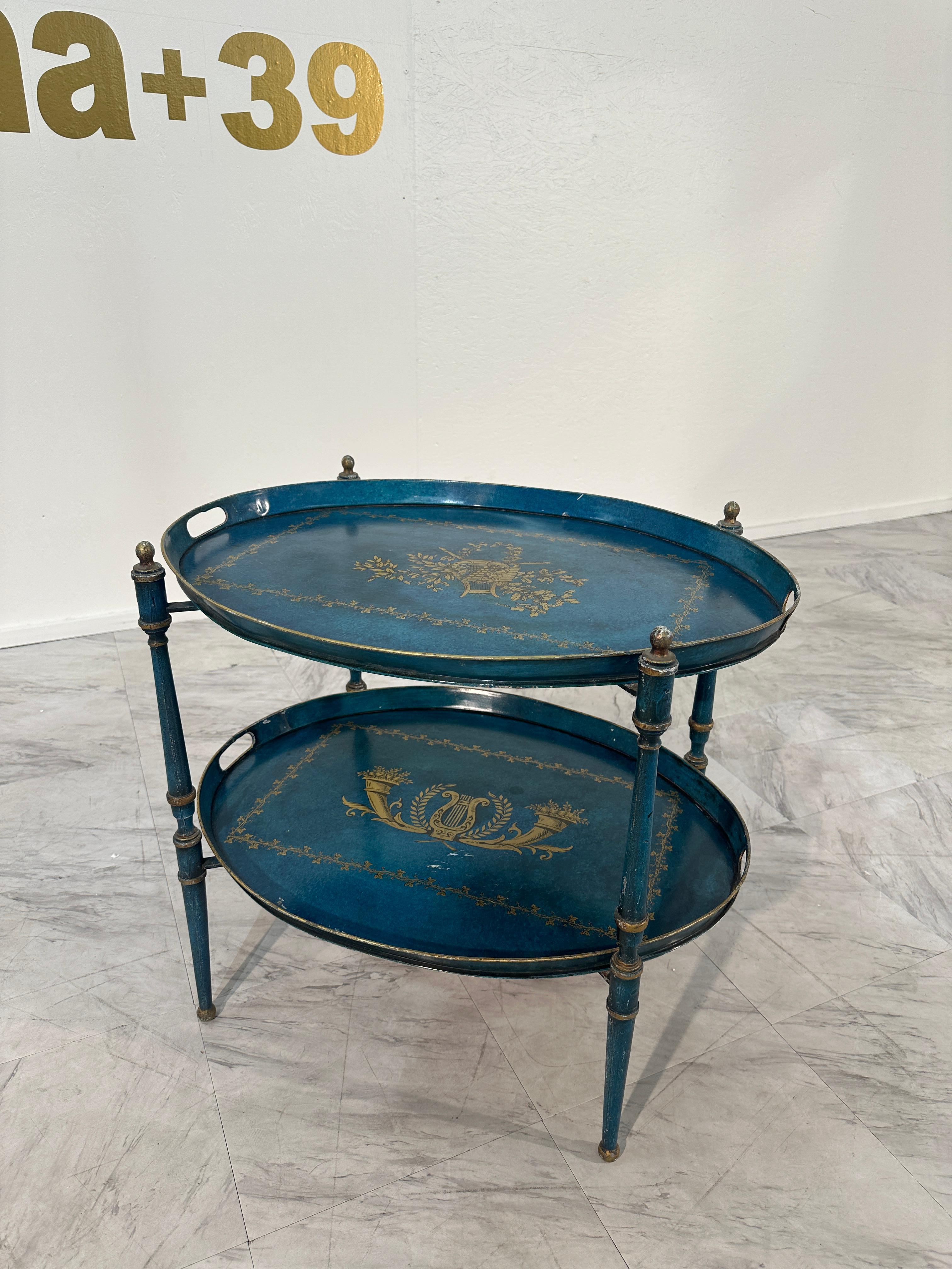 Vintage Italian Trolley with two removable trays, 50s

This metal trolley is a vintage piece featuring a frame designed to hold two decorative trays. The trays are elaborately painted in a rich blue tone with intricate gold detailing, showcasing a