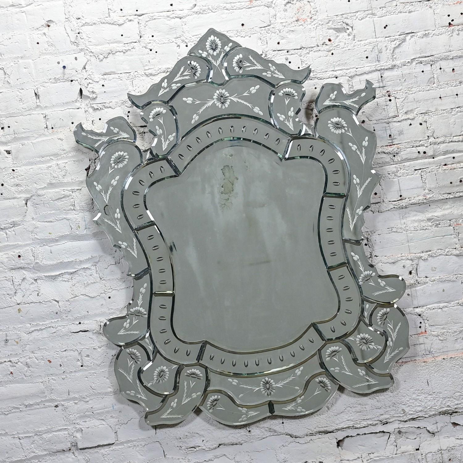 Exquis miroir mural en forme de bouclier sculpté et gravé en verre taillé vénitien du début au milieu du 20e siècle. Byit, en gardant à l'esprit qu'il s'agit d'une pièce vintage et non pas neuve, qui présentera donc des signes d'utilisation et