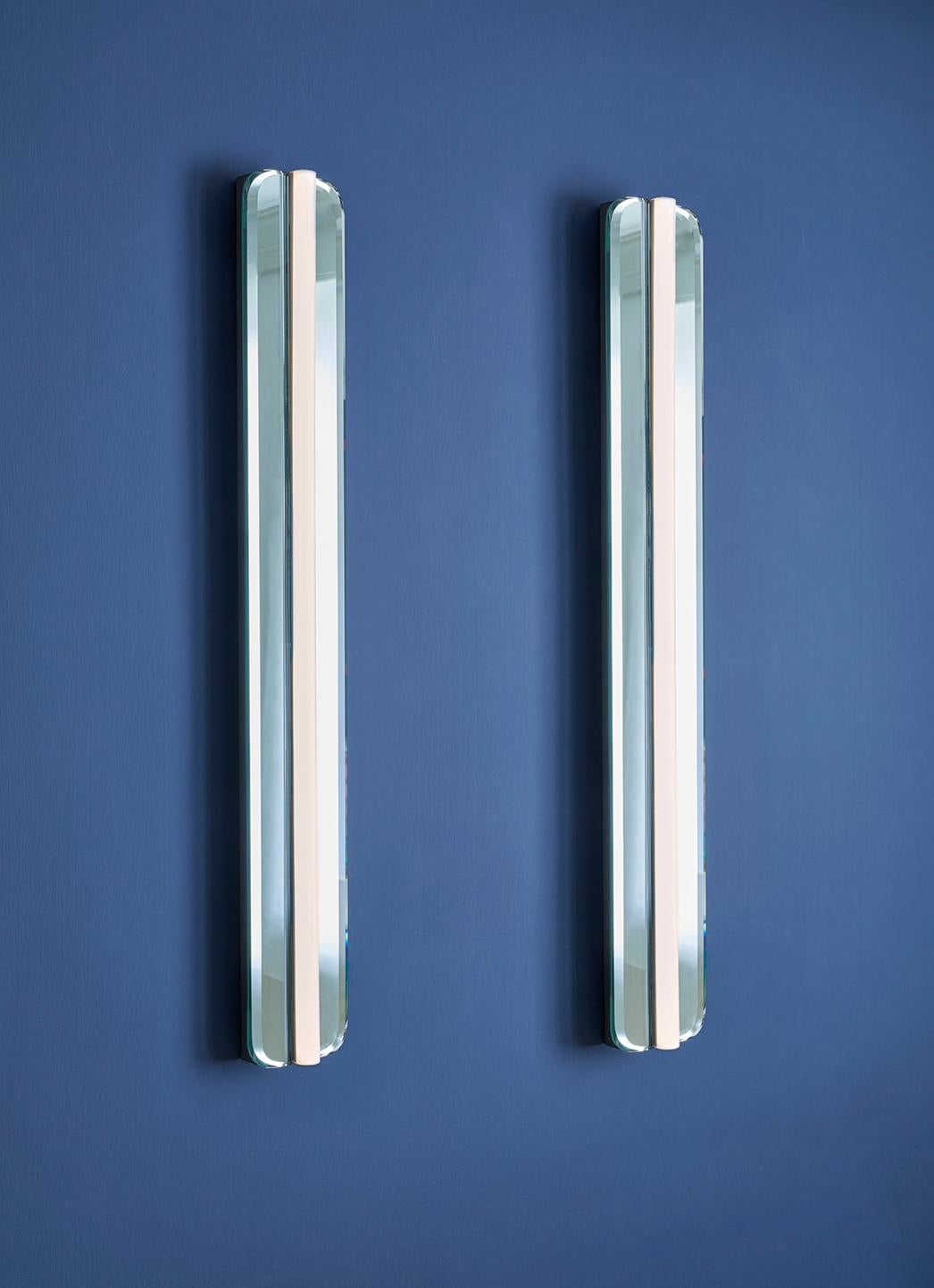 Decorative pair of elongated wall lights fixed on mirrored glass. Manufactured in Italy during the 1930s.
   