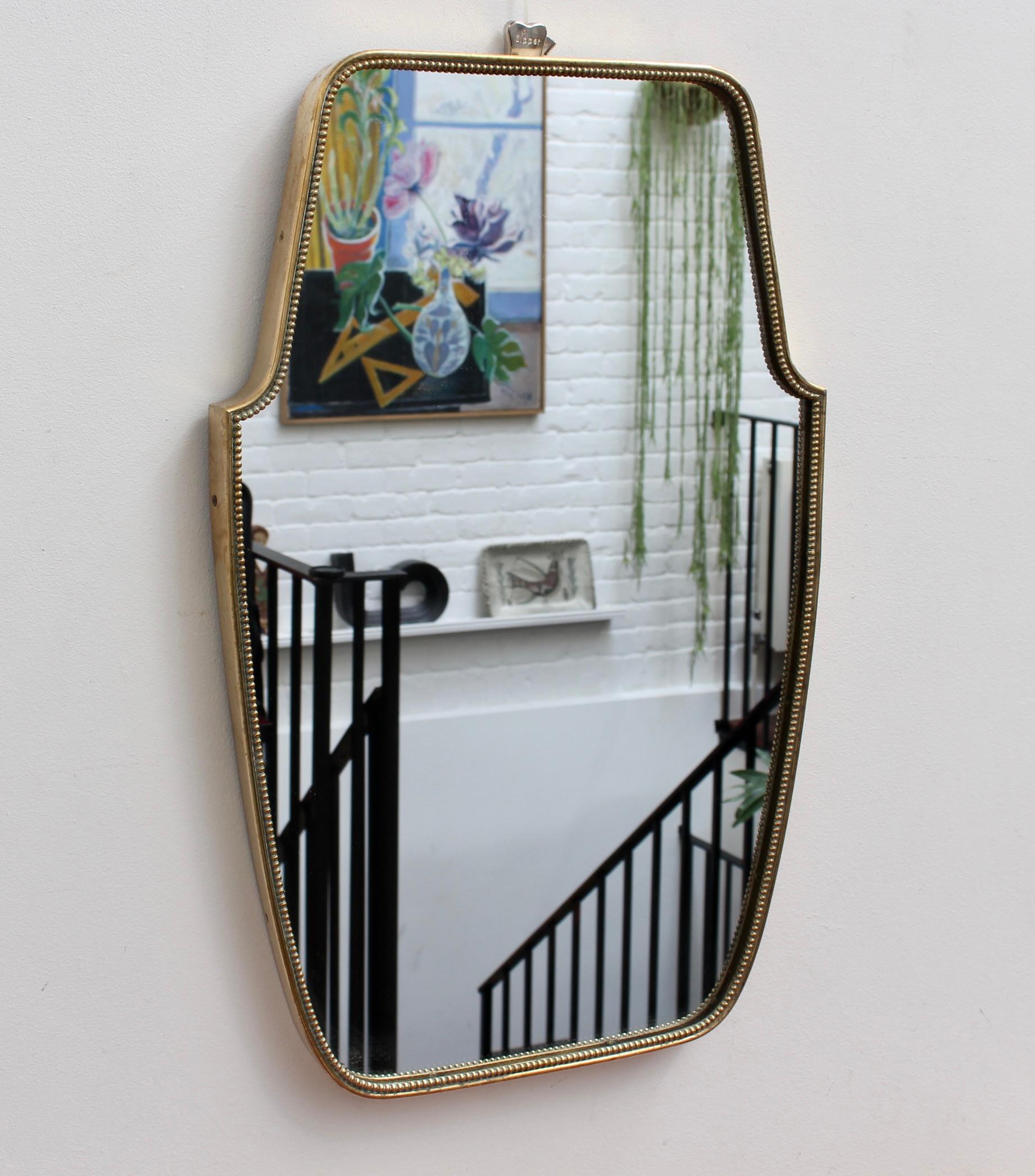 Mid-century Italian wall mirror with brass frame and beading (circa 1950s). This mirror is simply elegant and characterful in a modern, Gio Ponti style. It is small to medium sized, classically shaped, with a delightful beading adding visual