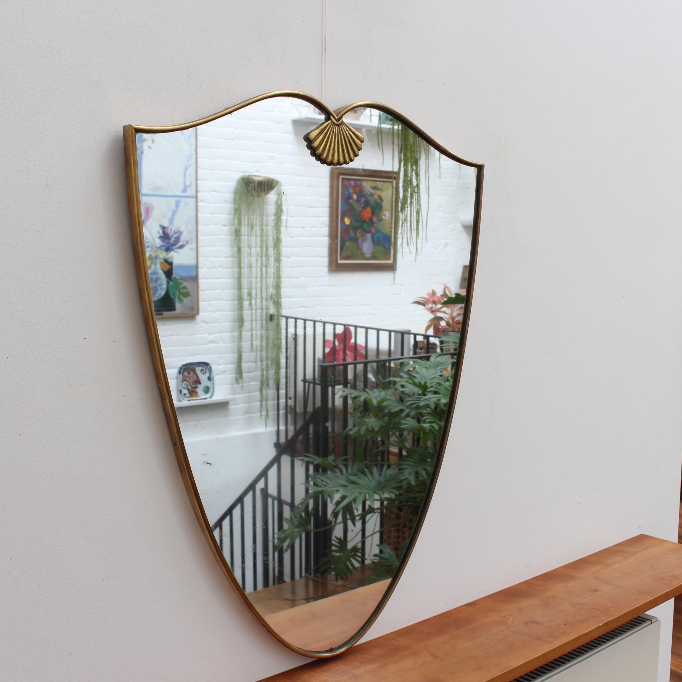 Vintage Italian wall mirror with brass frame (circa 1960s). The mirror is a unique shape with a rare seashell or fan feature which delights the viewer as an unexpected surprise. Always classically elegant in a modern Gio Ponti style. The piece is in