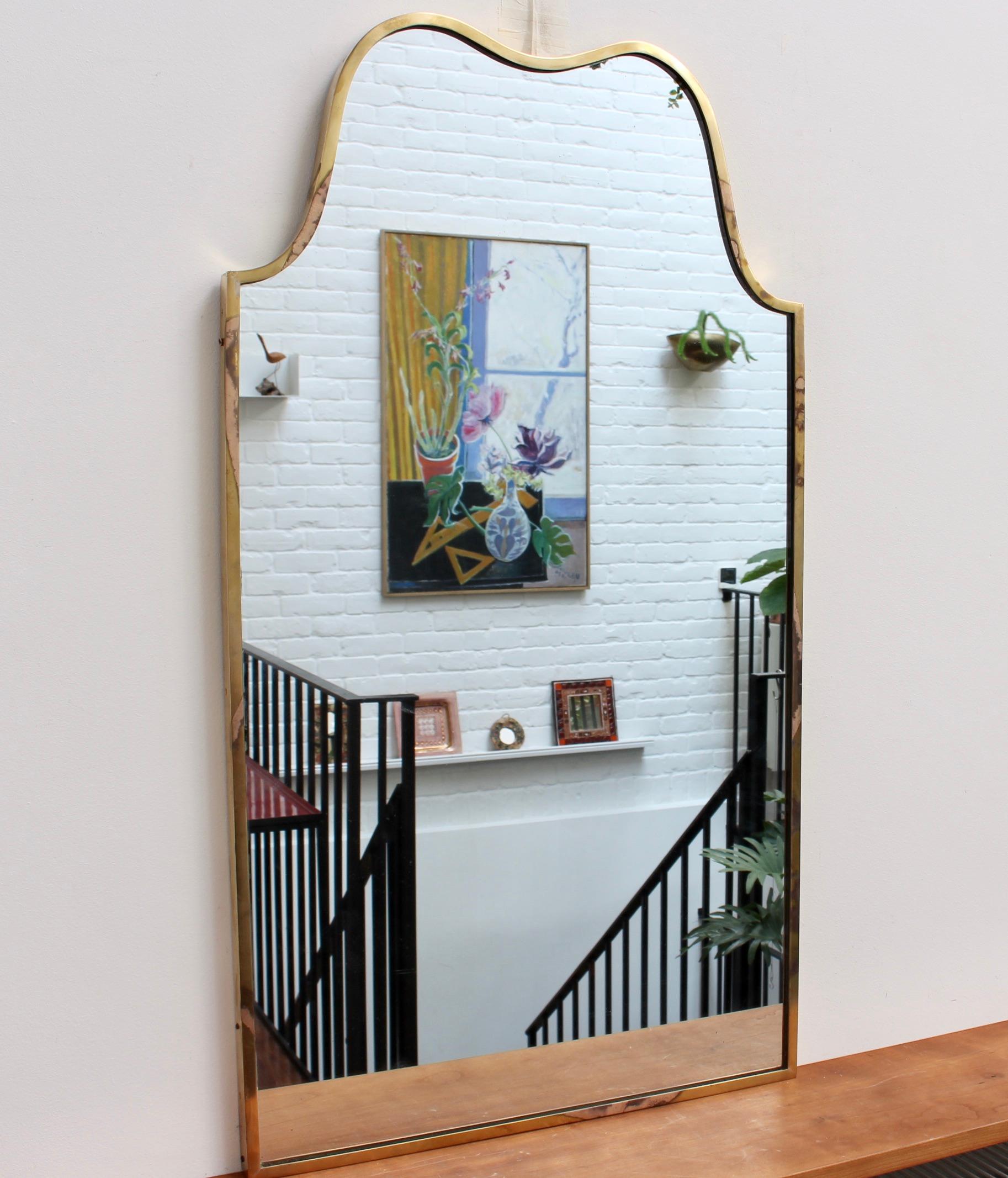 Vintage Italian wall mirror with brass frame, (circa 1950s). The unusual shape of this mirror lends it loads of character with its substantial weight and sensuous curves crowning the piece. It exudes personality, solidity, weightiness and has
