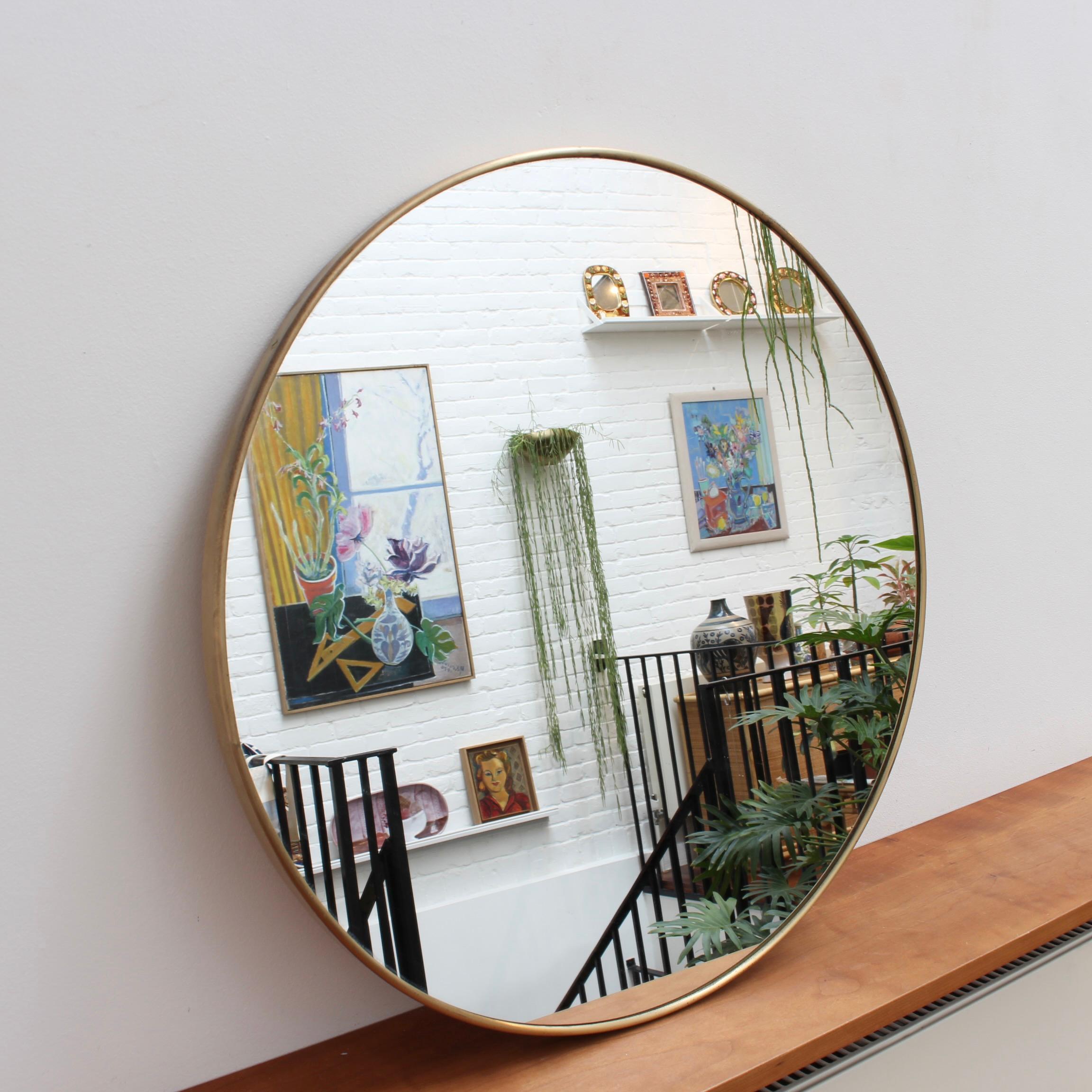 Mid-century Italian wall mirror with brass frame (circa 1950s). The mirror is perfectly round with a characterful brass frame. It is distinctive in a modern Gio Ponti style. The piece is in good vintage condition with a characterful patina on the