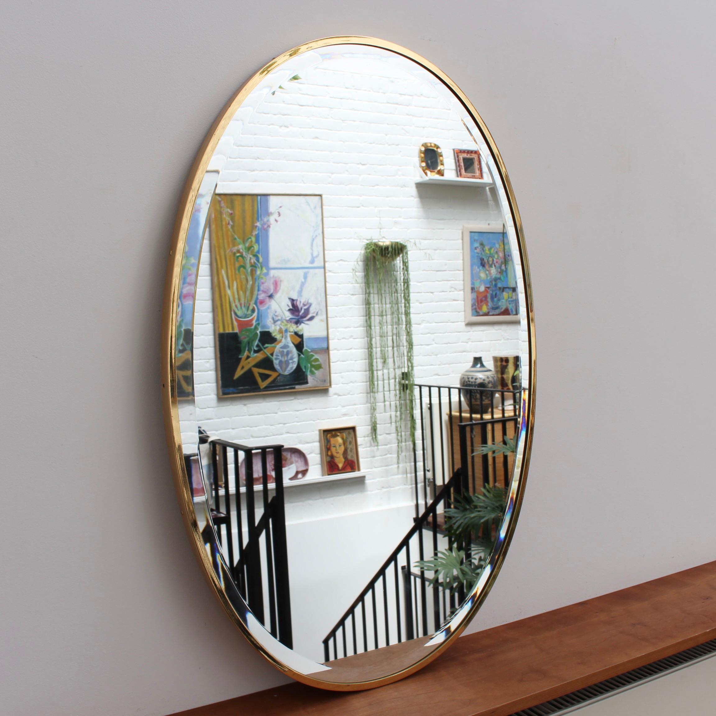 Mid-century Italian wall mirror with brass frame, circa 1950s. The bevelled mirror is oval in shape and very smart with irresistible durability. The visual impression is elegant and very distinctive in a modern Gio Ponti style. The mirror is in very