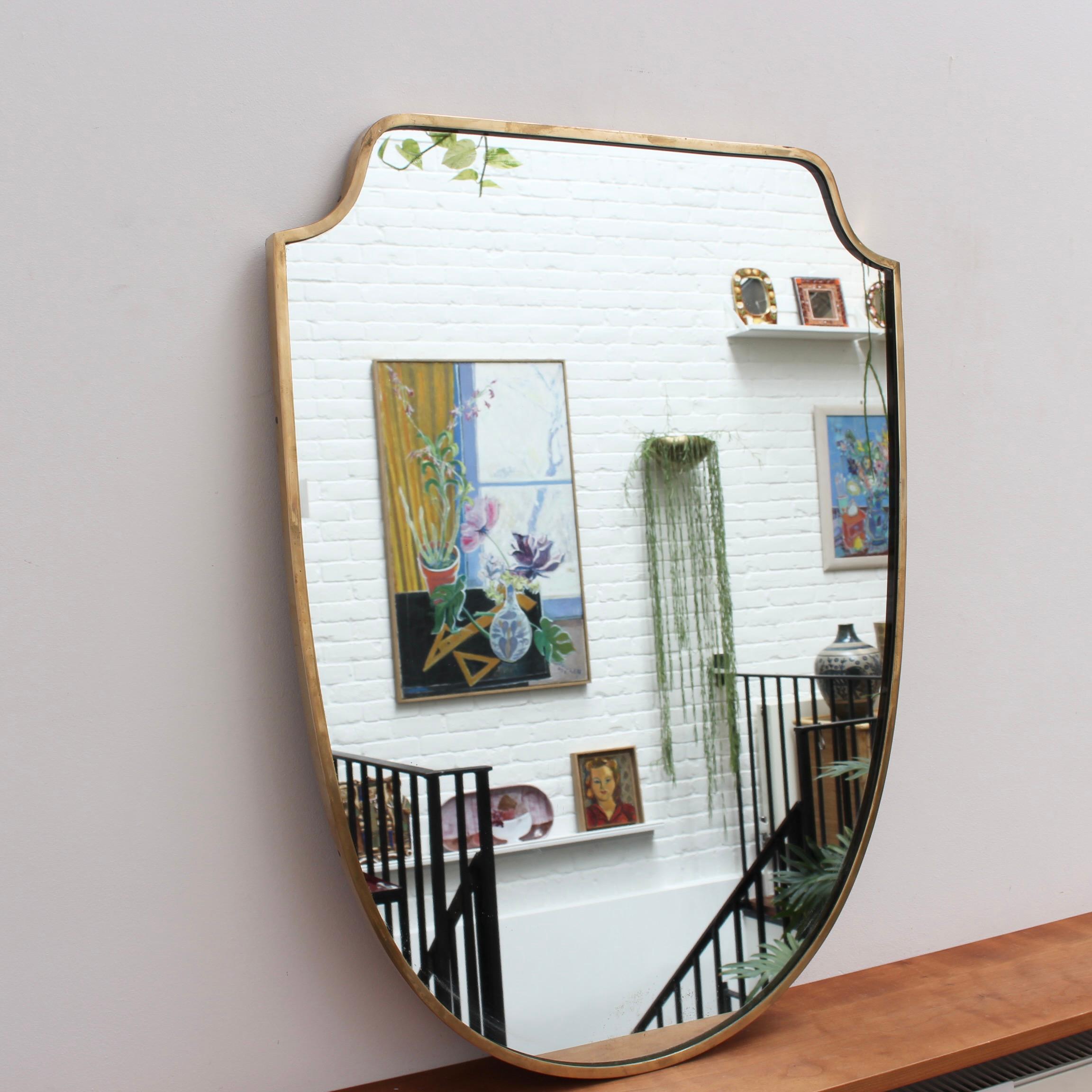 Mid-century Italian wall mirror with brass frame (circa 1950s). This mirror is simply elegant and characterful in a modern Gio Ponti style. It is crest-shaped and in good overall condition. There are some minor blemishes present on the lower portion