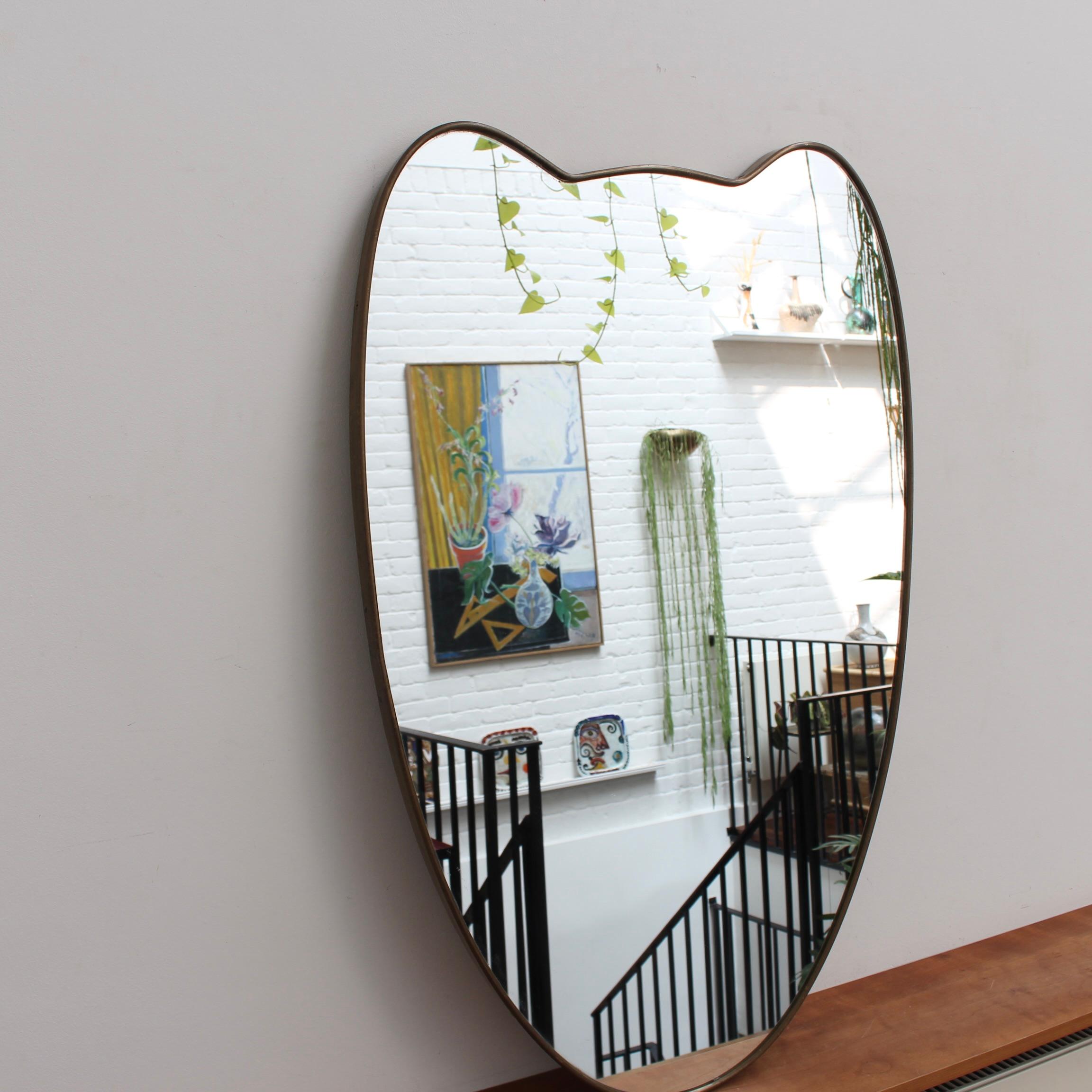Italienischer Wandspiegel aus der Mitte des Jahrhunderts mit Messingrahmen (ca. 1950). Der Spiegel ist klassisch geformt und zeichnet sich durch einen modernen Stil aus. Es ist insgesamt in gutem Zustand. Auf dem Messingrahmen entwickelt sich eine