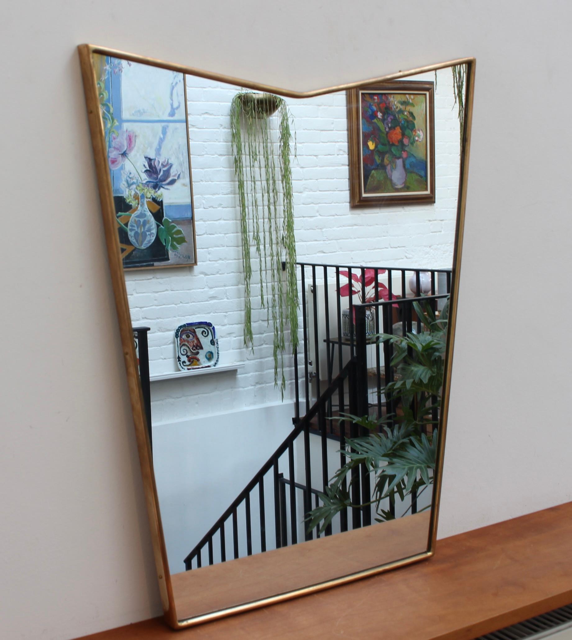 Mid-century Italian wall mirror with brass frame (circa 1950s). The smart, sturdy mirror sports a very original and delightful shape. Like other mirrors in this style, they are always classically elegant and distinctive. In good overall condition; a