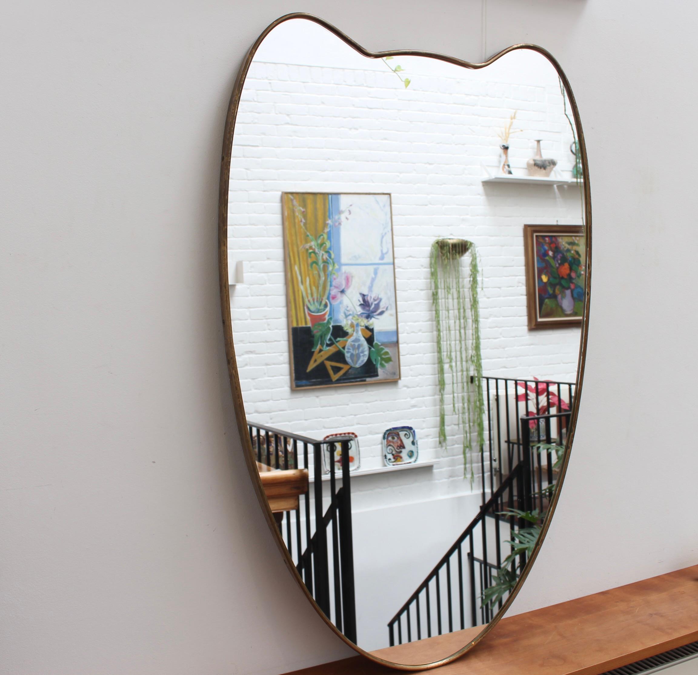 Italienischer Wandspiegel aus der Mitte des Jahrhunderts mit Messingrahmen (ca. 1950). Der Spiegel ist klassisch geformt und zeichnet sich durch einen modernen Stil aus. Es ist insgesamt in gutem Zustand. Auf dem Messingrahmen hat sich eine schöne
