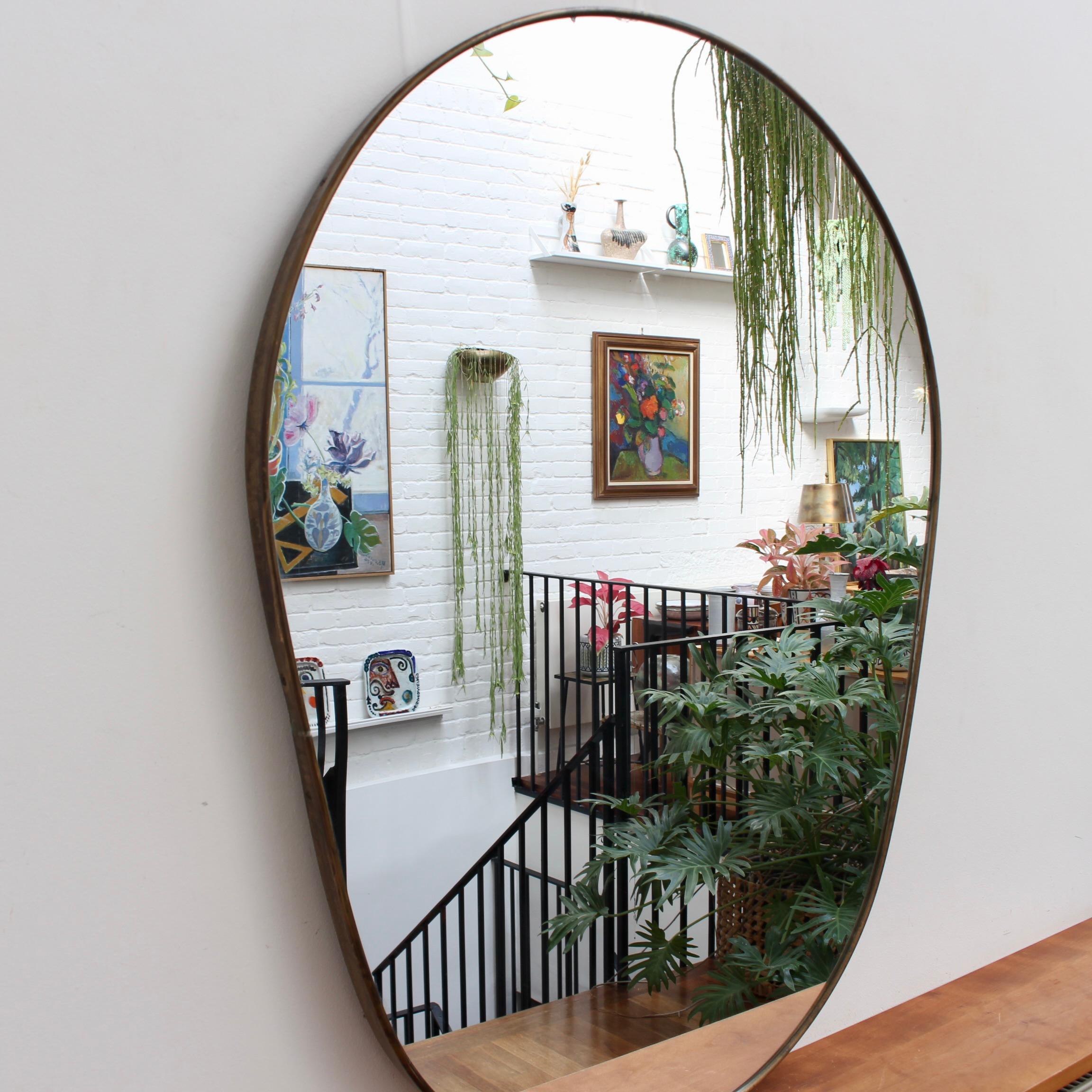 Italienischer Wandspiegel aus der Mitte des Jahrhunderts mit Messingrahmen (ca. 1950). Der Spiegel ist klassisch geformt und zeichnet sich durch einen modernen Stil aus. Auf dem Messingrahmen entwickelt sich eine schöne Patina - dieses Exemplar