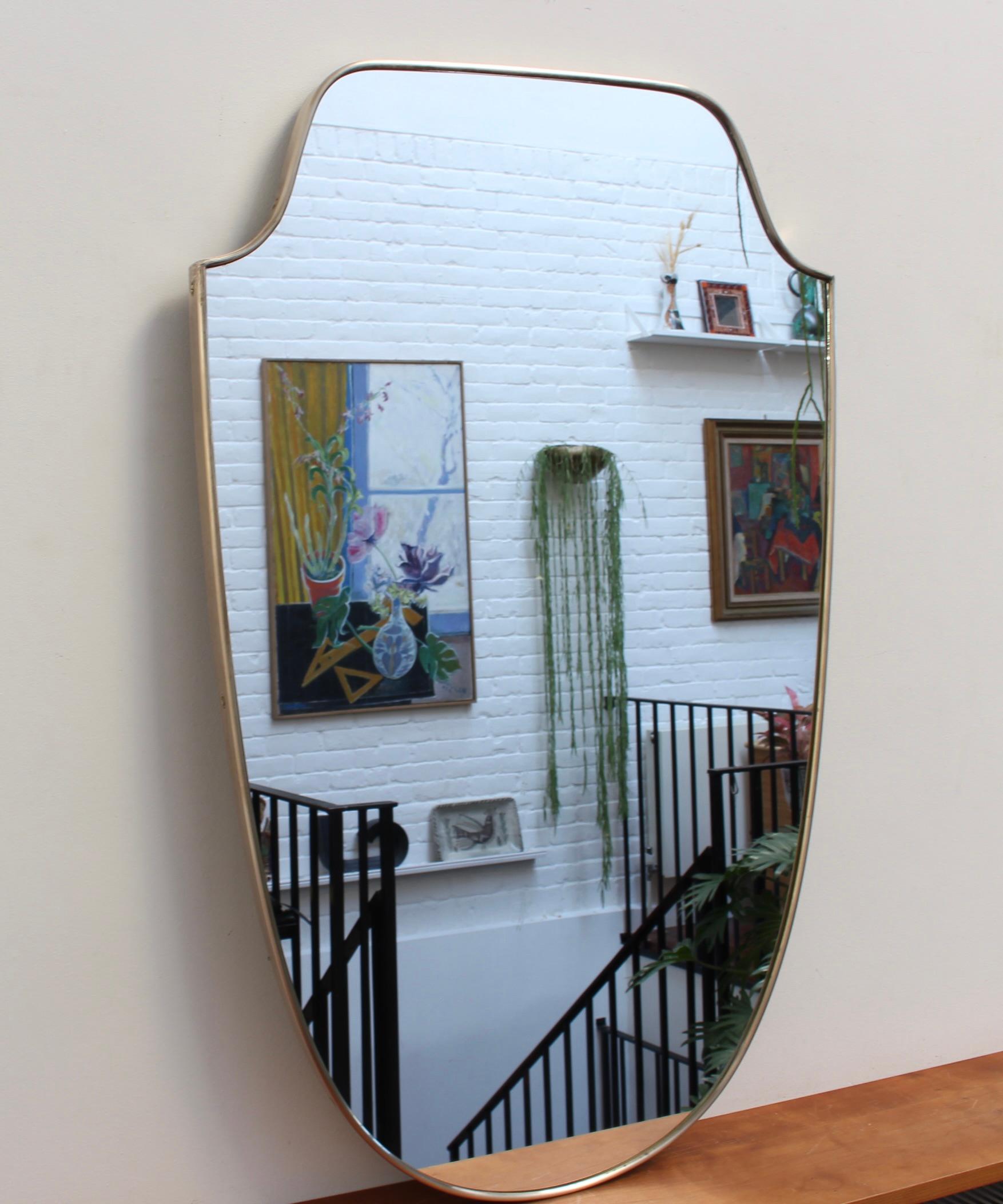 Mid-century Italian wall mirror with brass frame (circa 1950s). This is one of a pair of mirrors which are beautifully-shaped and distinctive in a Modern style. It is in good overall condition with the exception of a few small blemishes in the