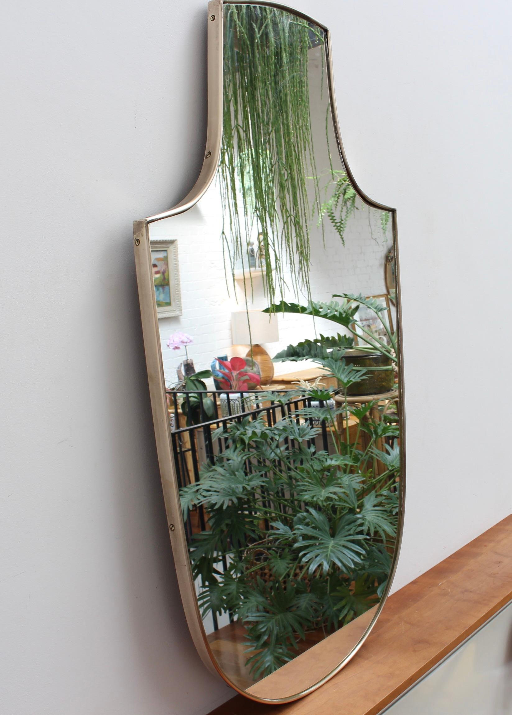 Midcentury Italian wall mirror with brass frame (circa 1950s). The mirror is classically-shaped and distinctive in a Modern style. It is in good overall condition with just a slight blemish on the glass (see photos). A beautiful patina develops on