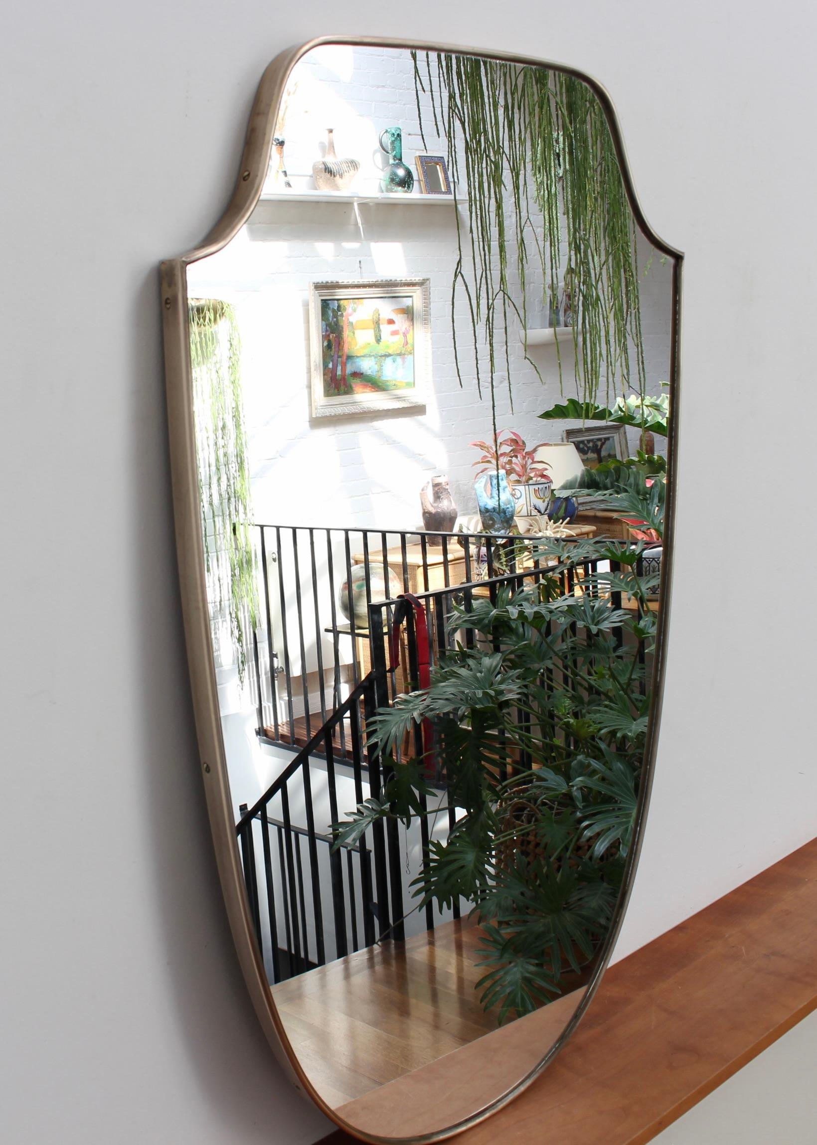 Midcentury Italian wall mirror with brass frame (circa 1950s). The large mirror is classically-shaped and distinctive in a Modern style. It is in good overall condition with two minor chips in the glass as seen in the accompanying photos. A