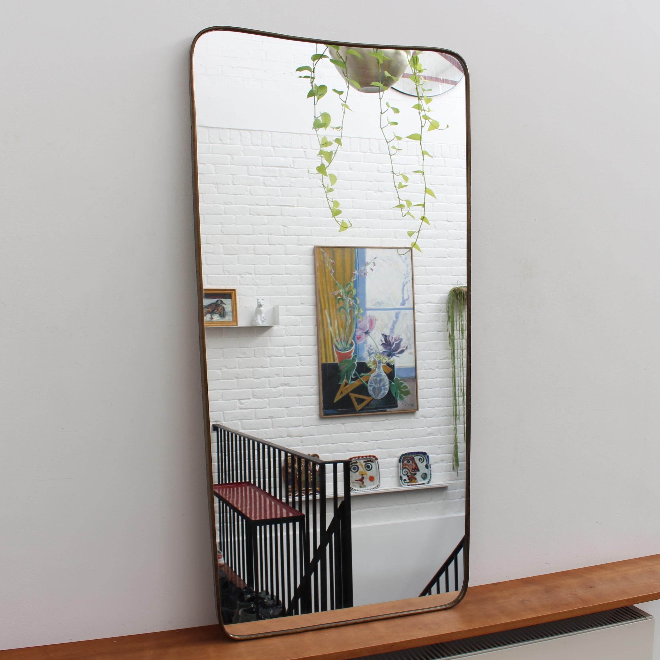 Mid-century large Italian wall mirror with brass frame (circa 1950s). The mirror is classically-shaped and distinctive in a Modern style. It is in good overall condition presenting just a small scratch on the glass giving it that extra vintage feel