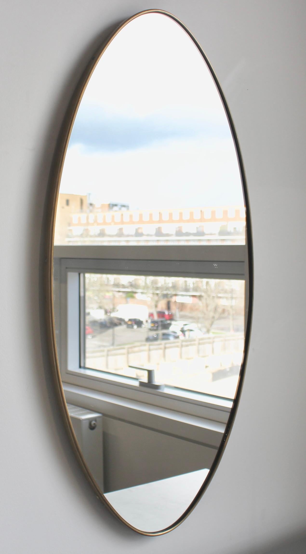 Miroir mural italien du milieu du siècle avec cadre en laiton (circa 1960s). Ce charmant miroir ovale est de forme classique et se distingue par son style moderne. Il est en bon état général, avec une patine noble qui s'est développée sur le cadre