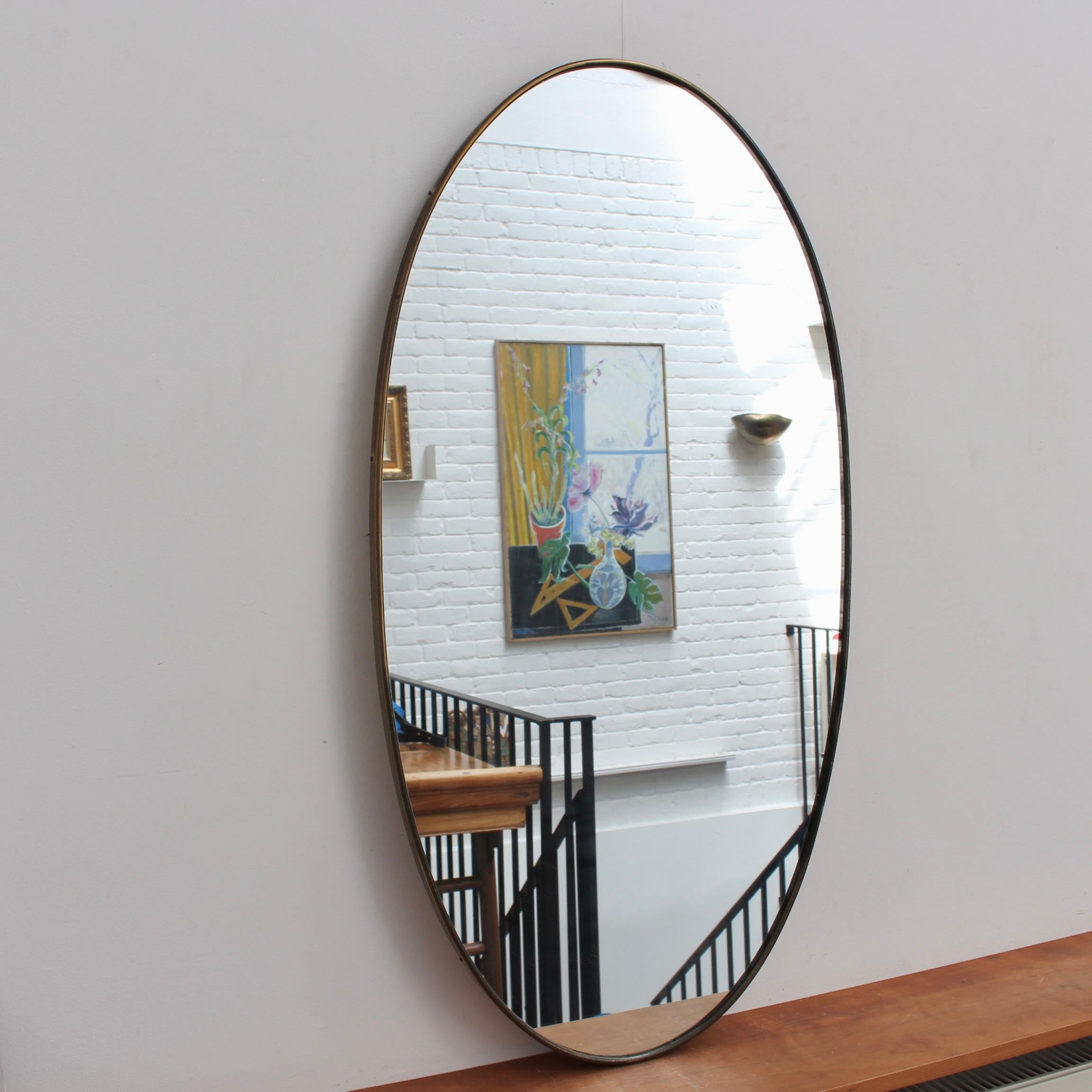 Miroir mural italien du milieu du siècle avec cadre en laiton (circa 1960s). Le miroir est de forme classique et se distingue par son style moderne. Une patine noble se développe sur le cadre en laiton - ainsi que quelques entailles et marques liées