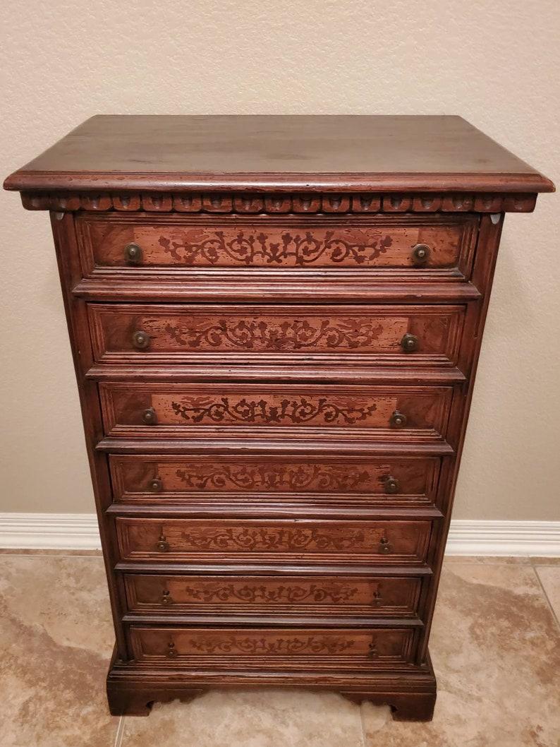 A vintage Italian semainier, handcrafted and carved walnut, fitted with seven drawers, each with scrolling foliate marquetry, rising on bracket feet. circa 20th century; Italy. 

A semainier is a tall, sometimes narrow, chest of drawers, typically