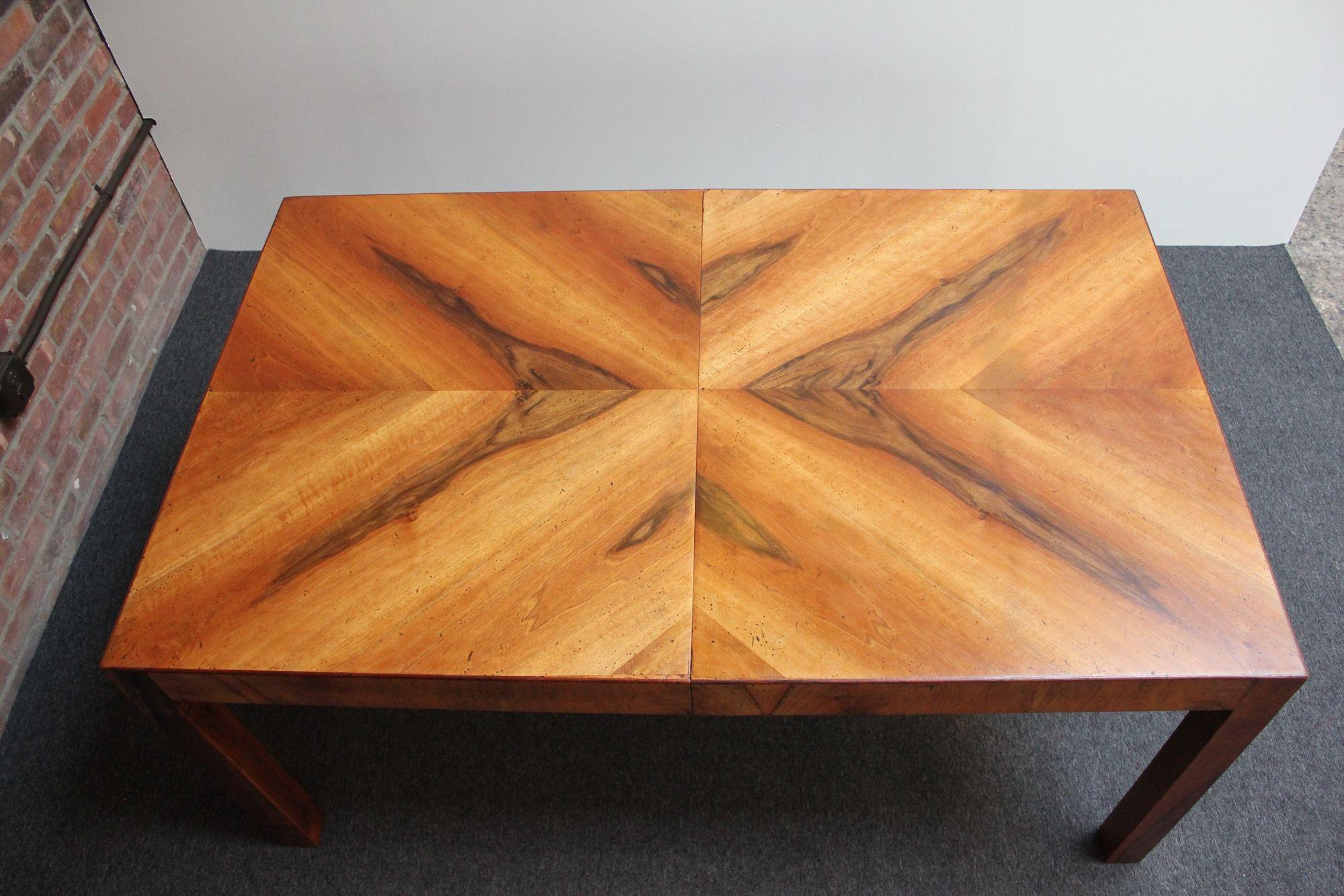Visually striking Italian walnut Parsons-style extendable dining table with two leaves (ca. 1970, Italy).
Spectacular wood grain forming a a chevron pattern on both ends of the table.
Two additional leaves have a contrasting veneer with the grain