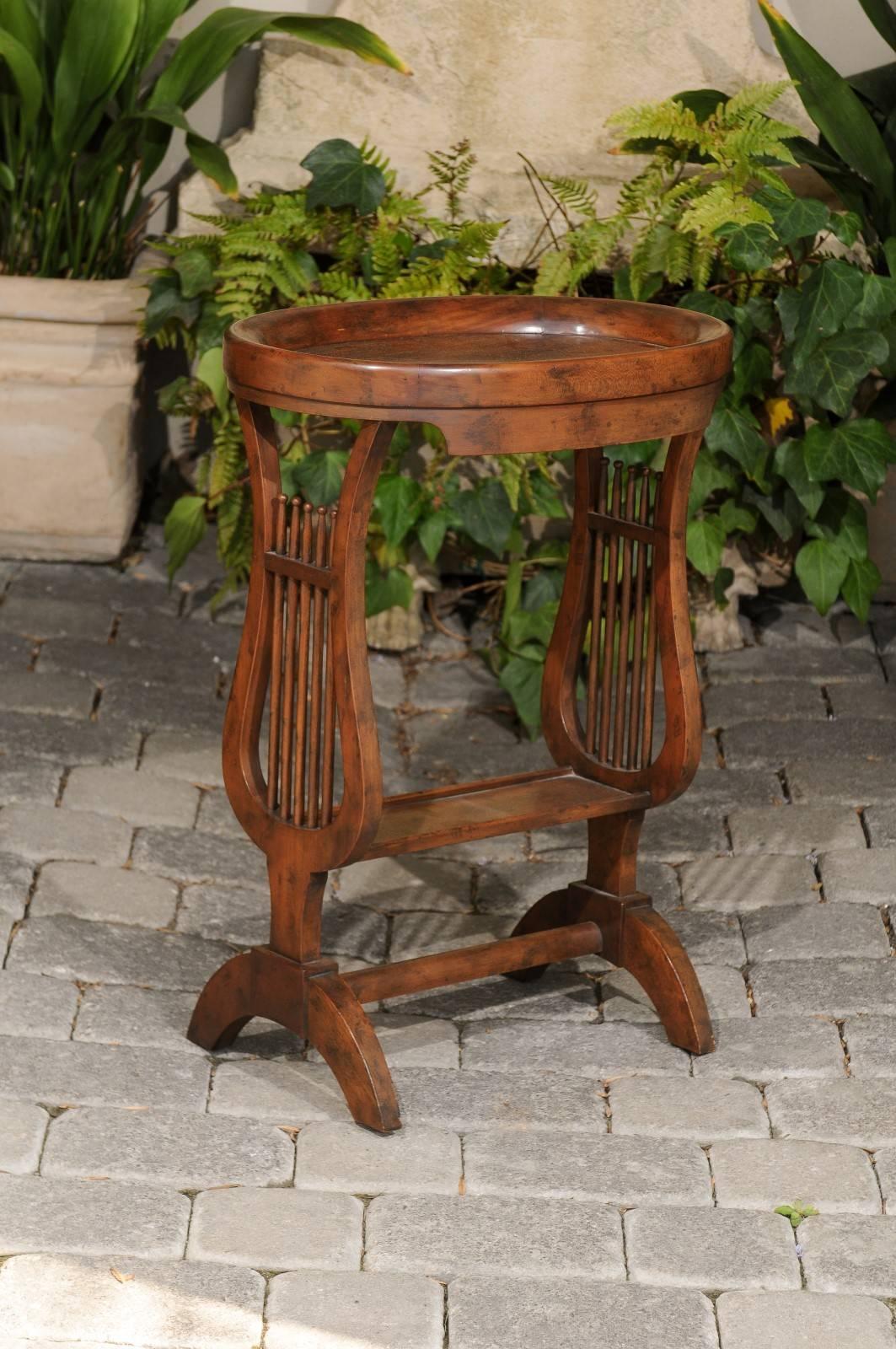 An Italian vintage walnut side table with oval tray top and lyre-shaped legs from the mid-20th century. This Italian side table features an oval tray top, supported by two elegantly carved lyre-shaped legs. Playing the role of a stretcher, a narrow
