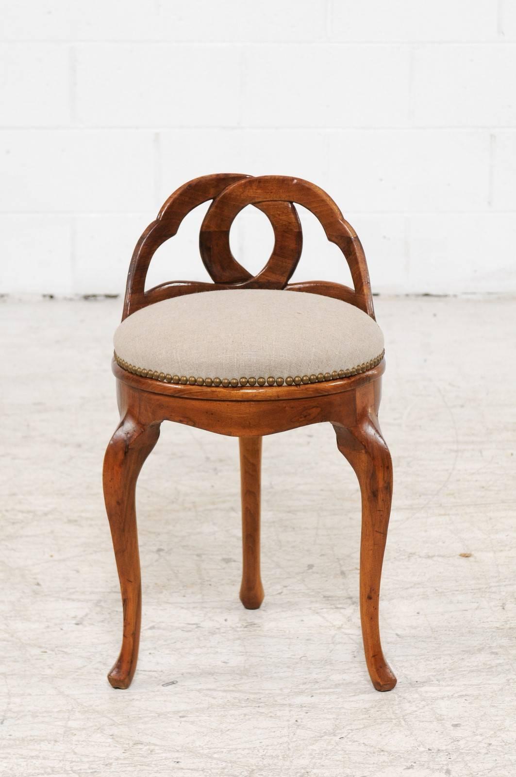 An Italian vintage round walnut upholstered stool with carved back and cabriole legs from the mid-20th century. This exquisite Italian walnut stool features an unusual carved back, made of two intertwining motifs. The circular seat has been