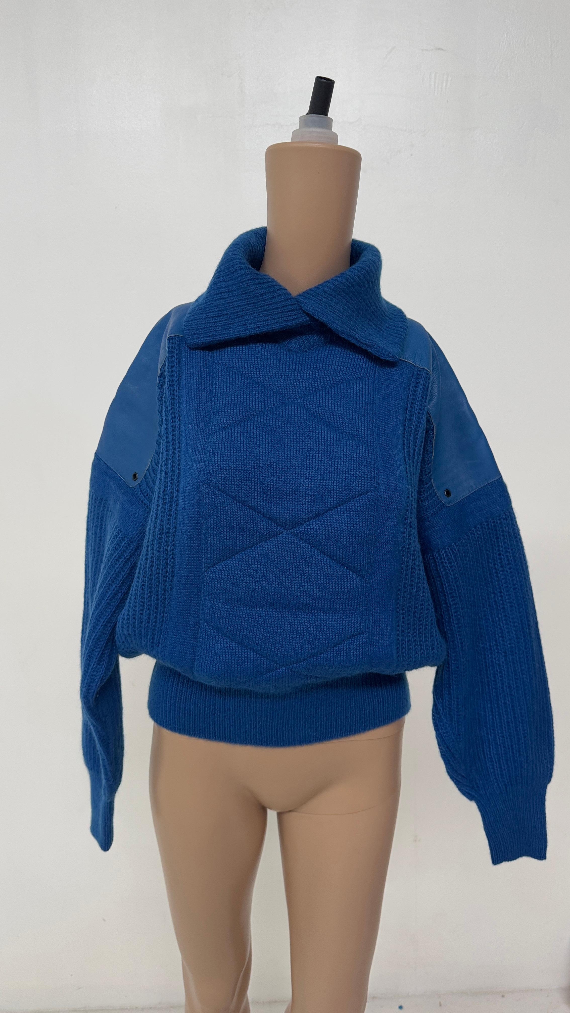 This striking 1980s Italian vintage sweater embodies bold design and tactile contrast. Crafted in a vibrant electric blue pure wool knit, the garment features a dynamic central quilted panel on both front and back, adding structure and geometric