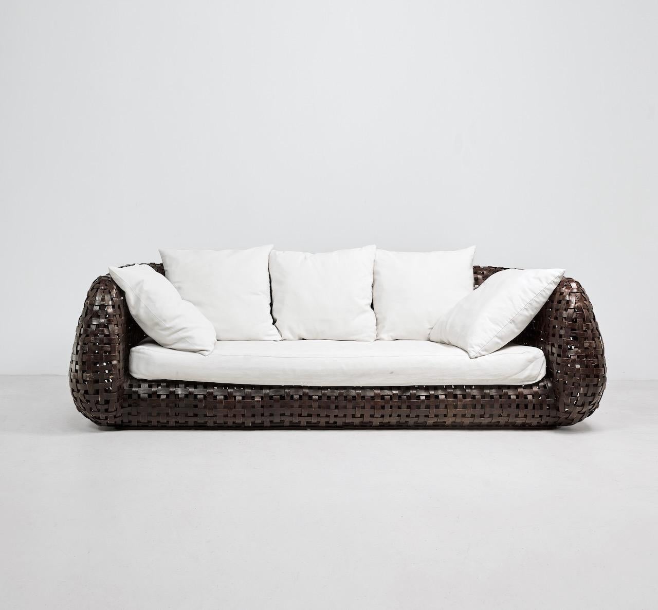 Sofa aus dem späten 20. Jahrhundert, bestehend aus geflochtenem Rattan auf einem Bambusrahmen. Dazu gibt es ein Kissen, das mit einem cremefarbenen Baumwollstoff bezogen ist. 


Abmessungen (cm, ca.): 
Höhe: 70
Breite: 228
Tiefe: 111
