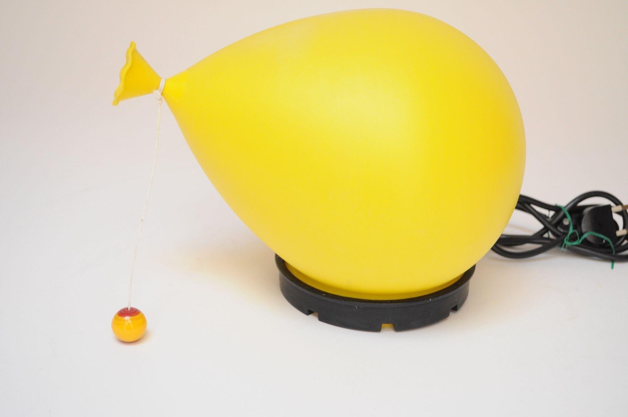 Whimsical yellow plastic balloon wall sconce/table lamp designed by Yves Christin for Bilumen (ca. 1970s, Italy).
The balloon fixture sits slanted on its black base (fixed, not removable) giving the impression of 'floating.' Can be mounted in a