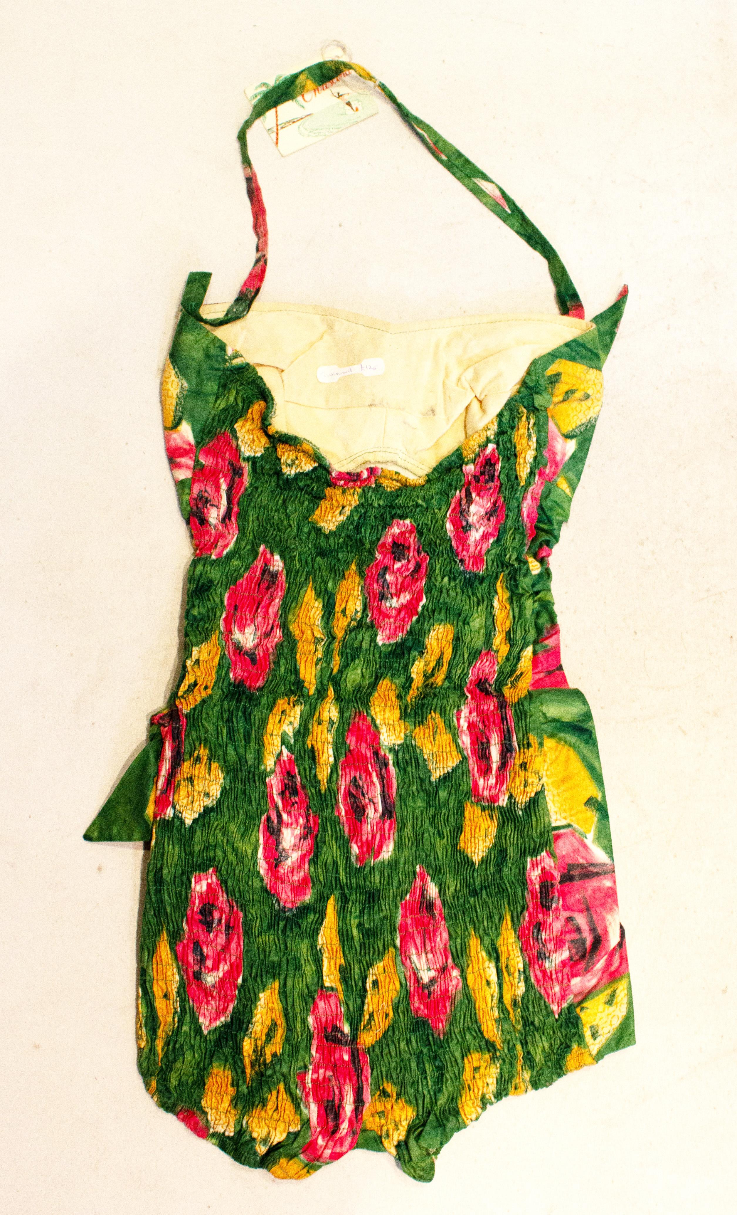 A charming vintage 'Its a Christina ' swimsuit. The costume is in a wonderful print of green , pink and caramel, and can be worn as a halterneck or strapless. It has  gathering at the back, and a bow on the right breast and left hip. It is style