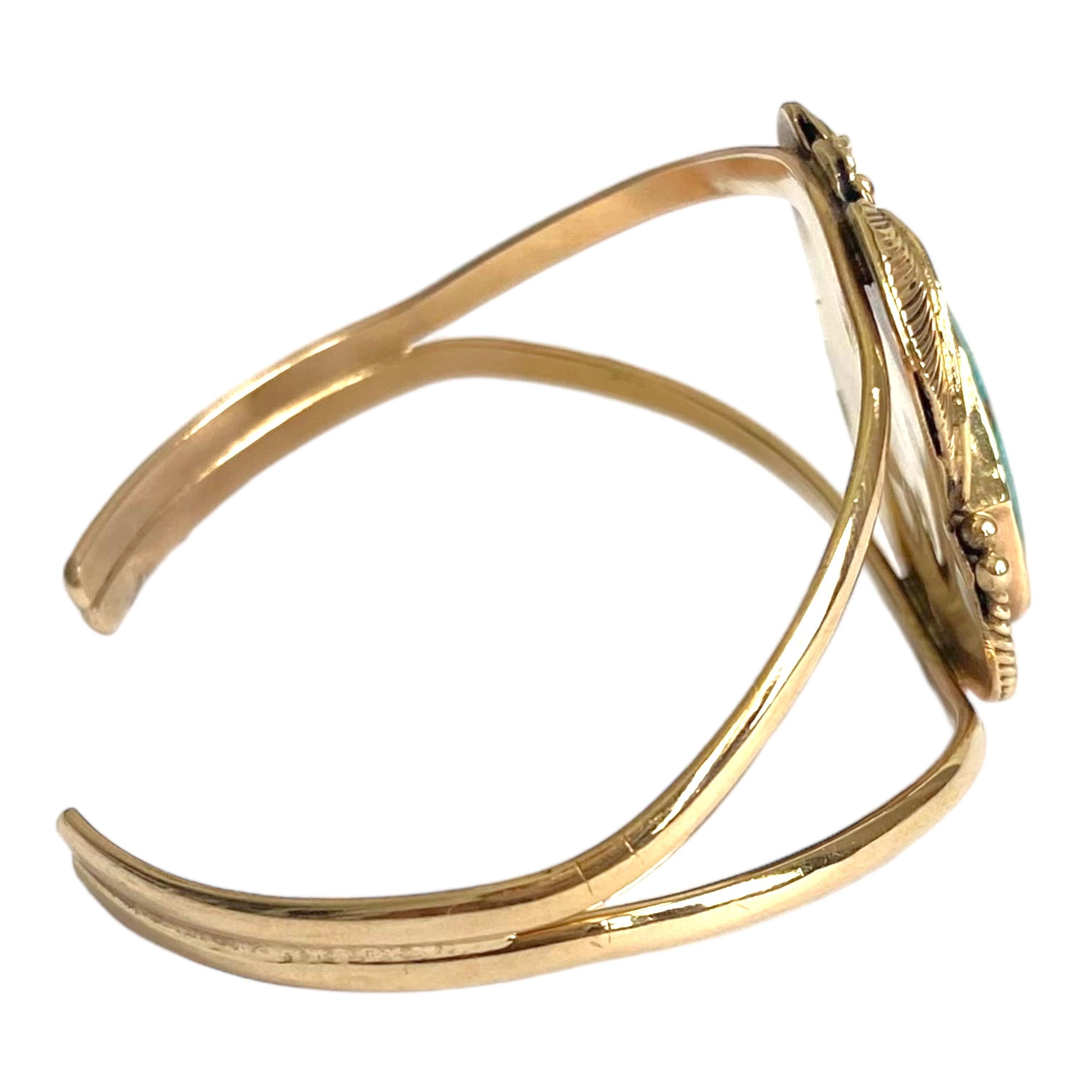 14K yellow gold IVAN V Navajo cuff bracelet, featuring a bezel set American turquoise decorated with a feather design and encircled with twisted gold wires and balls.
Measurements:
Front: 31 mm H x 28 mm W x 5.5 mm D
Inner circumference: 6