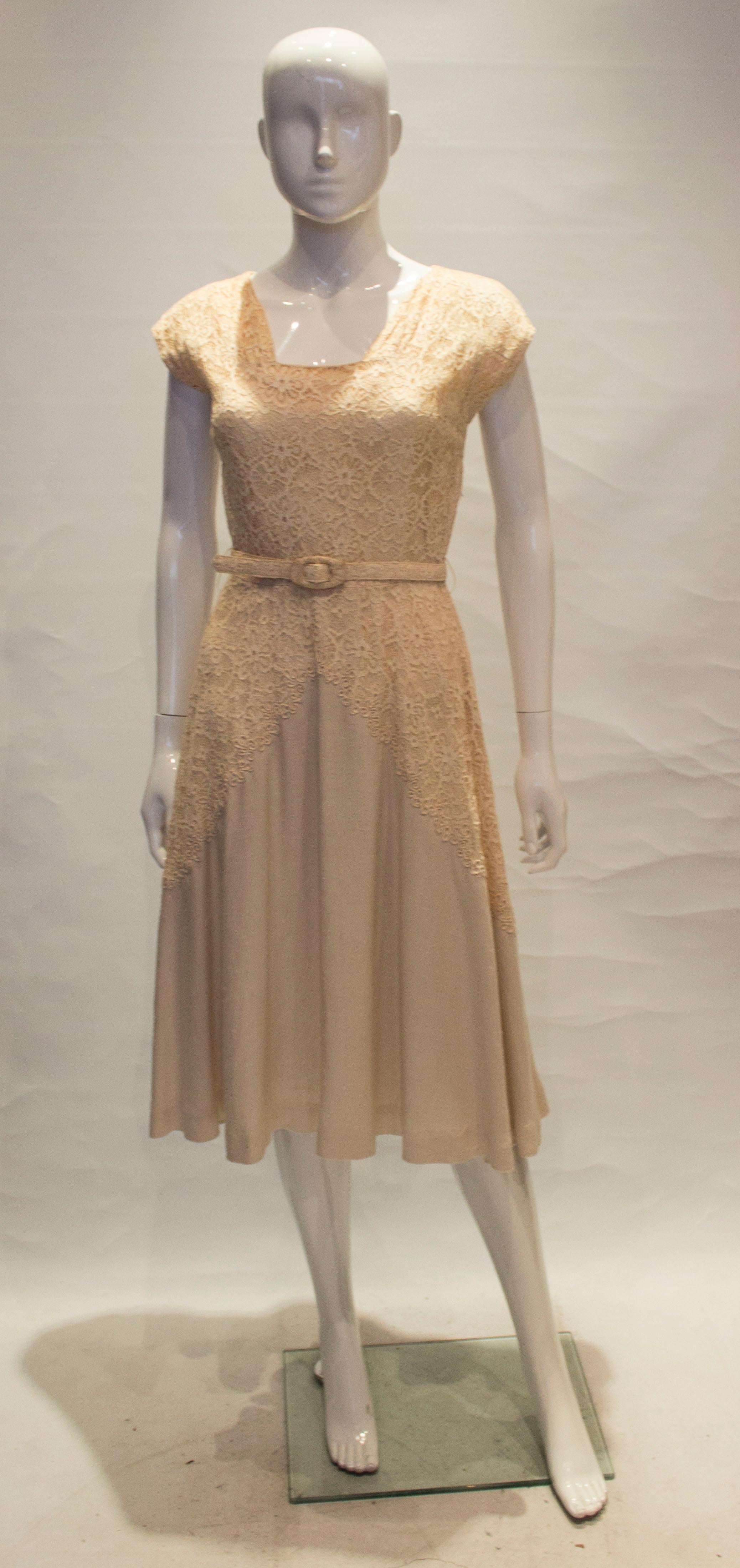 A pretty vintage dress by Well Made , London. The dress has a square neckline, and lace detail on the front and back. it has a self fabric belt , full skirt and is partly lined.

