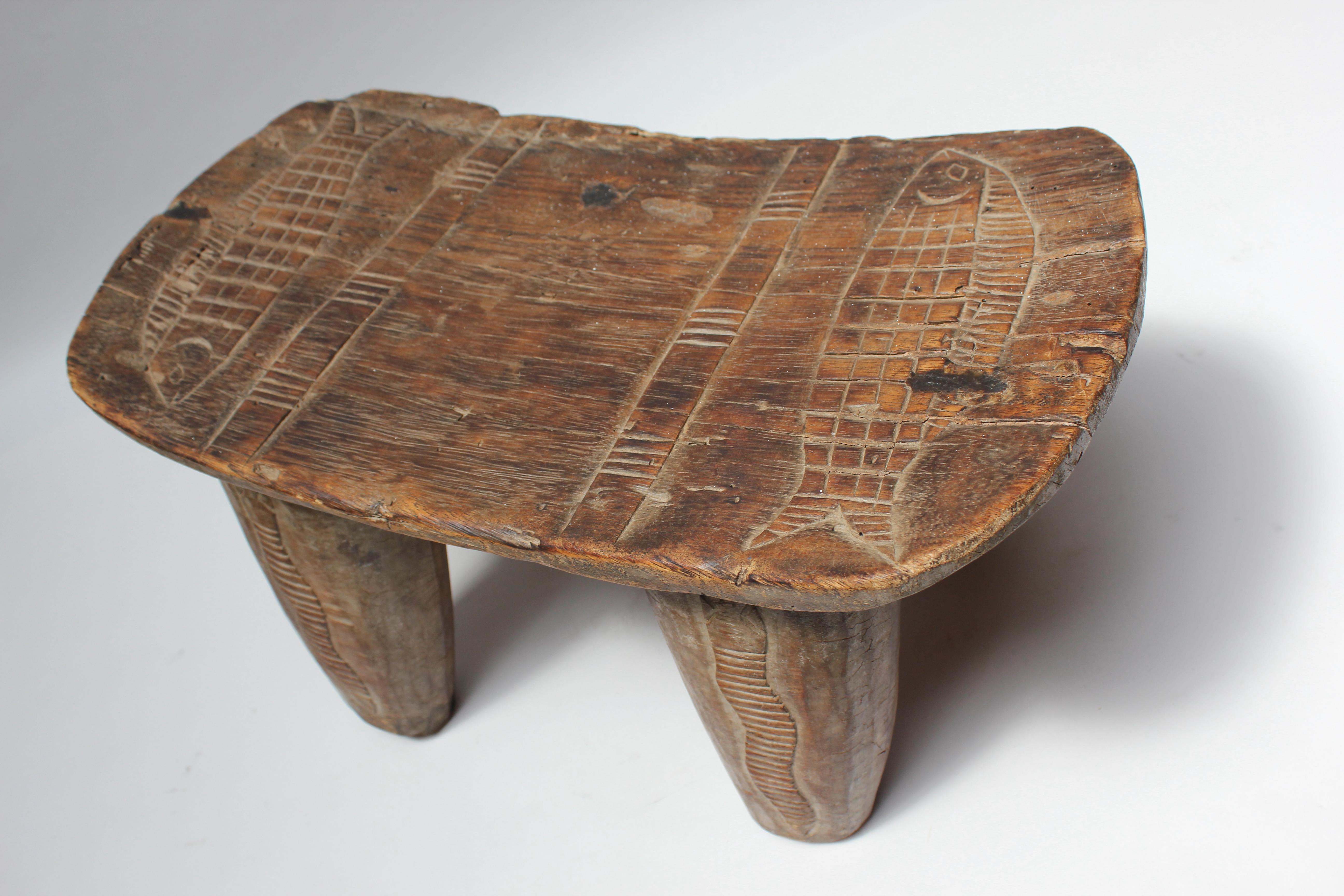 Senufo stool supported by thick, sculptural legs (Ivory Coast, Africa, ca. 1950). Carved snake and fish details present with nice patina / wear consistent with age along with gouges and spots of wood loss, as shown. 
H: 11