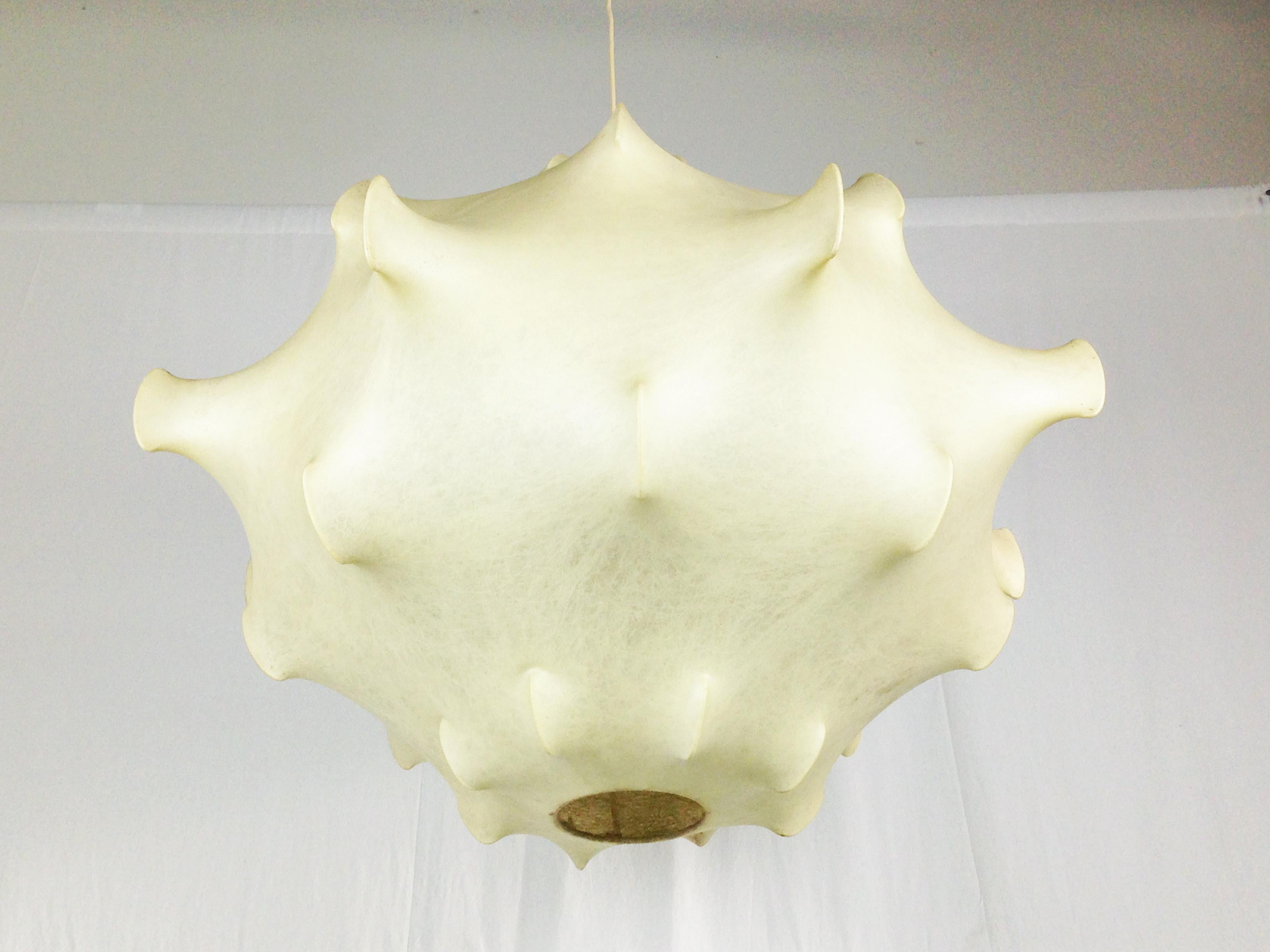 This vintage taraxacum pendant lamp was designed by Castiglioni brothers (Achille, Pier Giacomo e Livio) and belongs to the early production period. Overall good condition. The cocoon covering is yellowed due to time and shows light defects on the