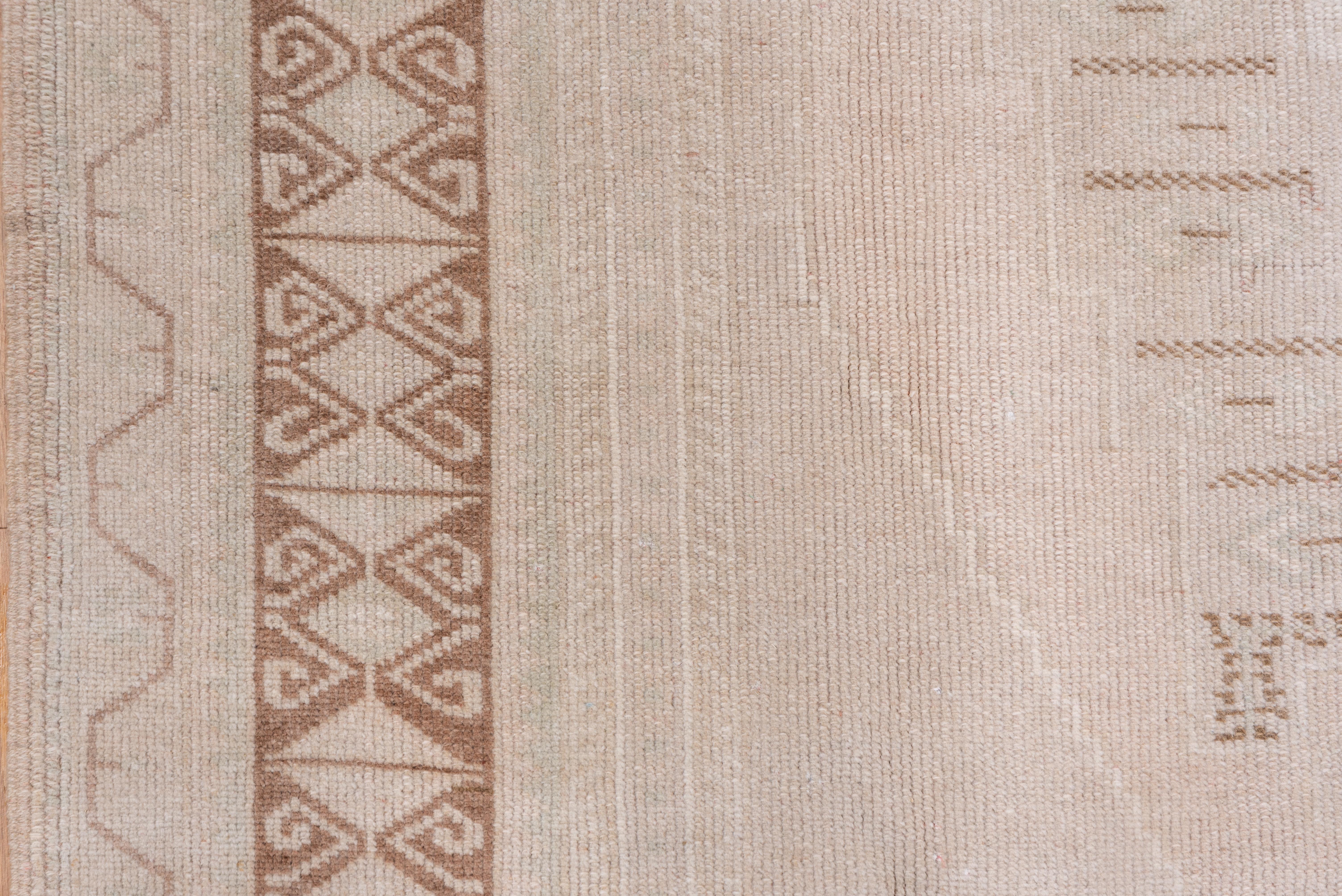 This a decoratively light Anatolian large scatter in tones of sand, cream and brown, with undulating wave Meander extra panels at the field ends. Light brown border of divided lozenge.