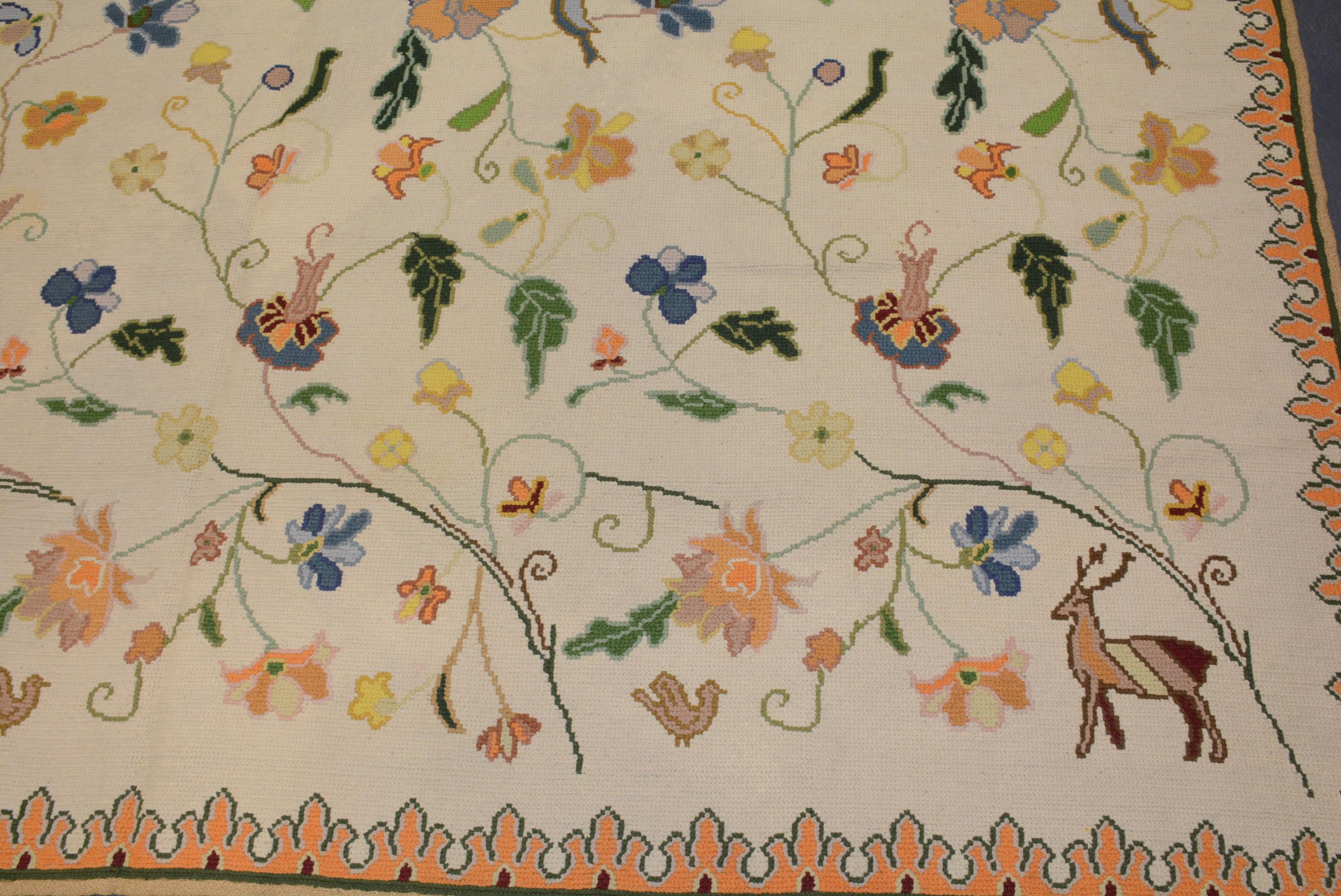 A large vintage Portuguese needlepoint carpet with animals and birds amongst foliage on an ivory field within a narrow border utilizing an Arraiolos cross-stitch weave. In very good overall condition, 17' 4